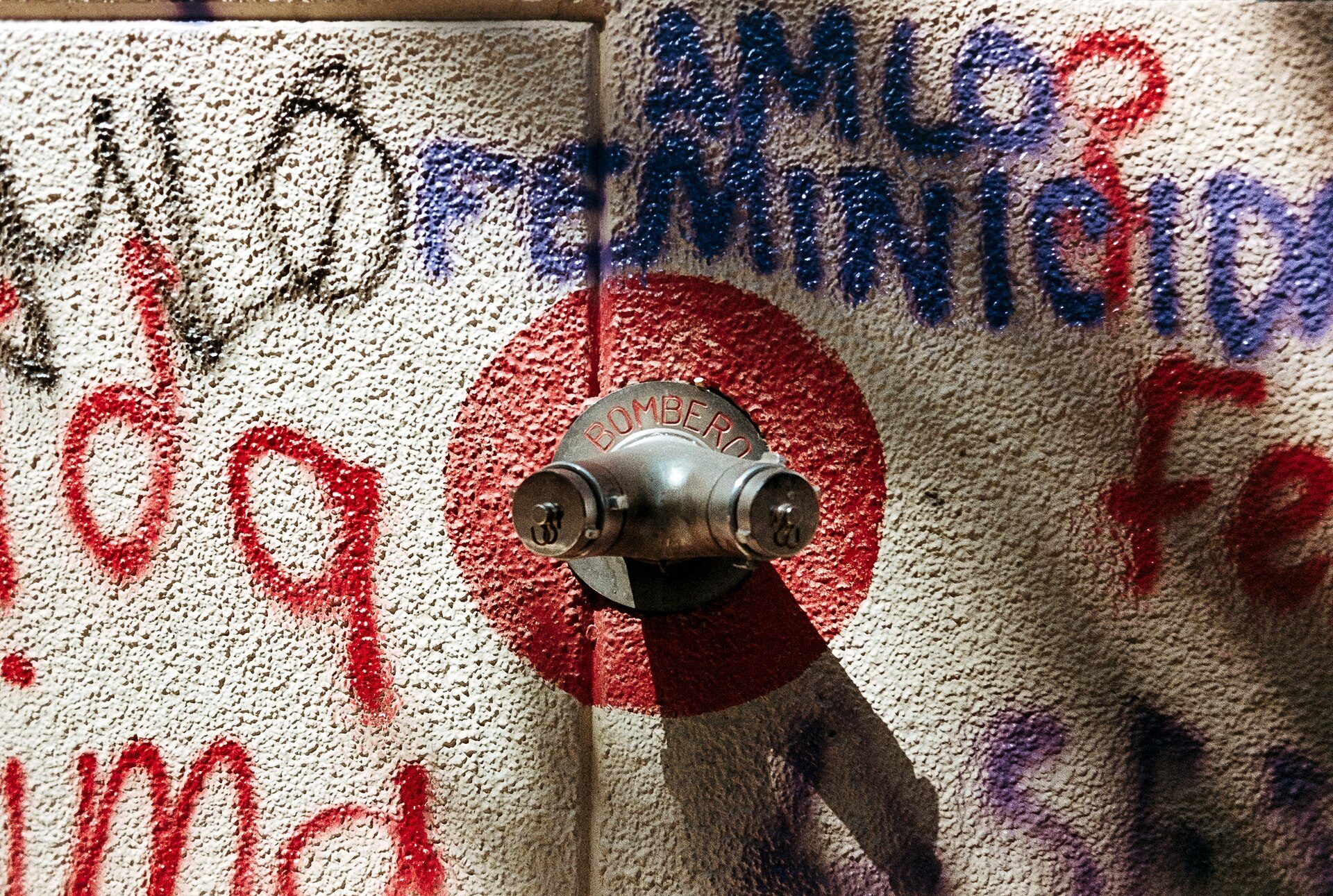A graffiti-covered wall with a metal pipe and a red circle.