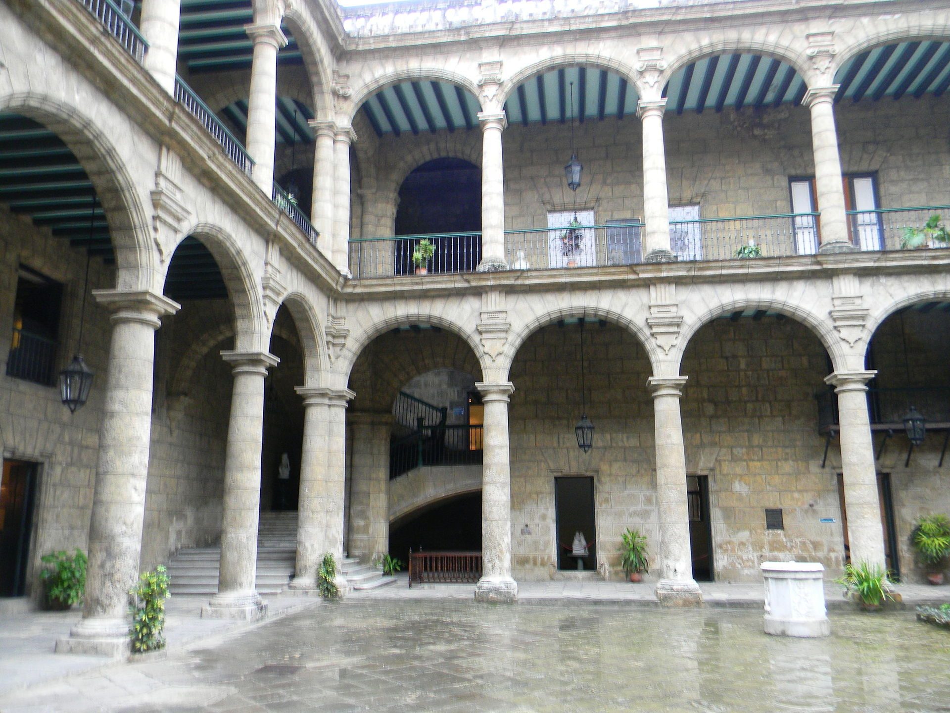 Alt text: Courtyard with arched colonnade, stone walls, and upper balcony.