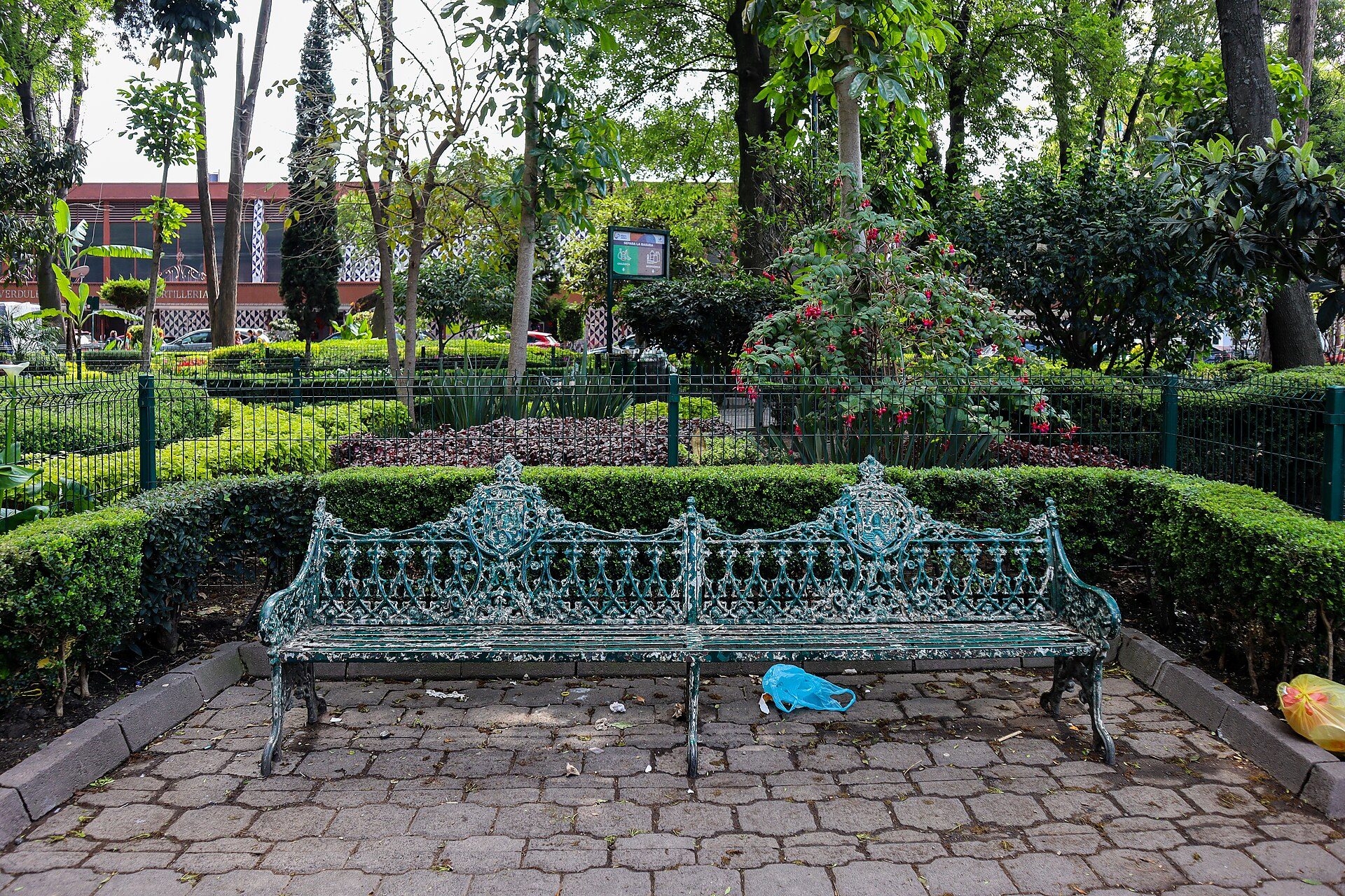 A green park bench surrounded by trees and flowers.