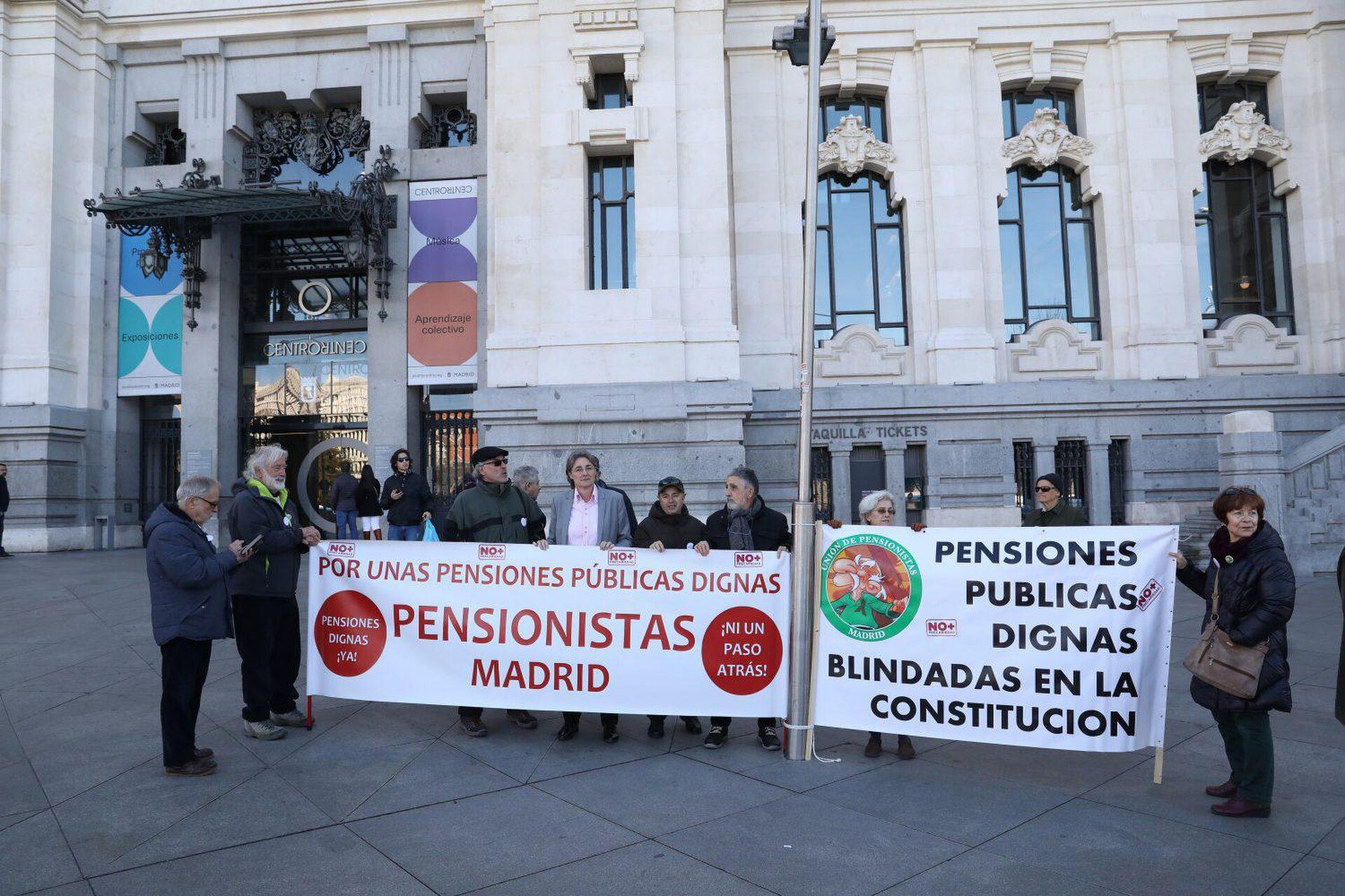 A group of people holding signs in front of a large building.