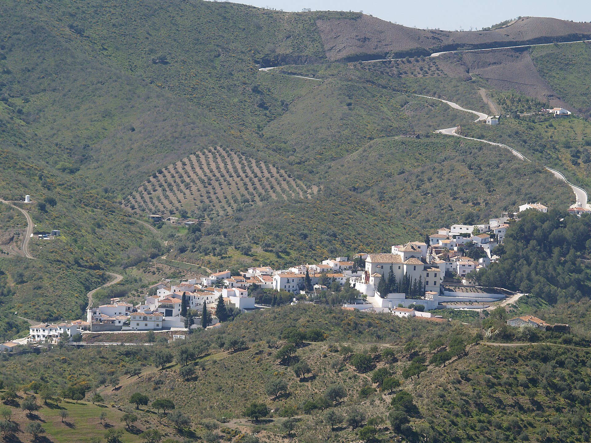 Alt text: White-walled room with scenic mountain and vineyard view, featuring a balcony and modern amenities.