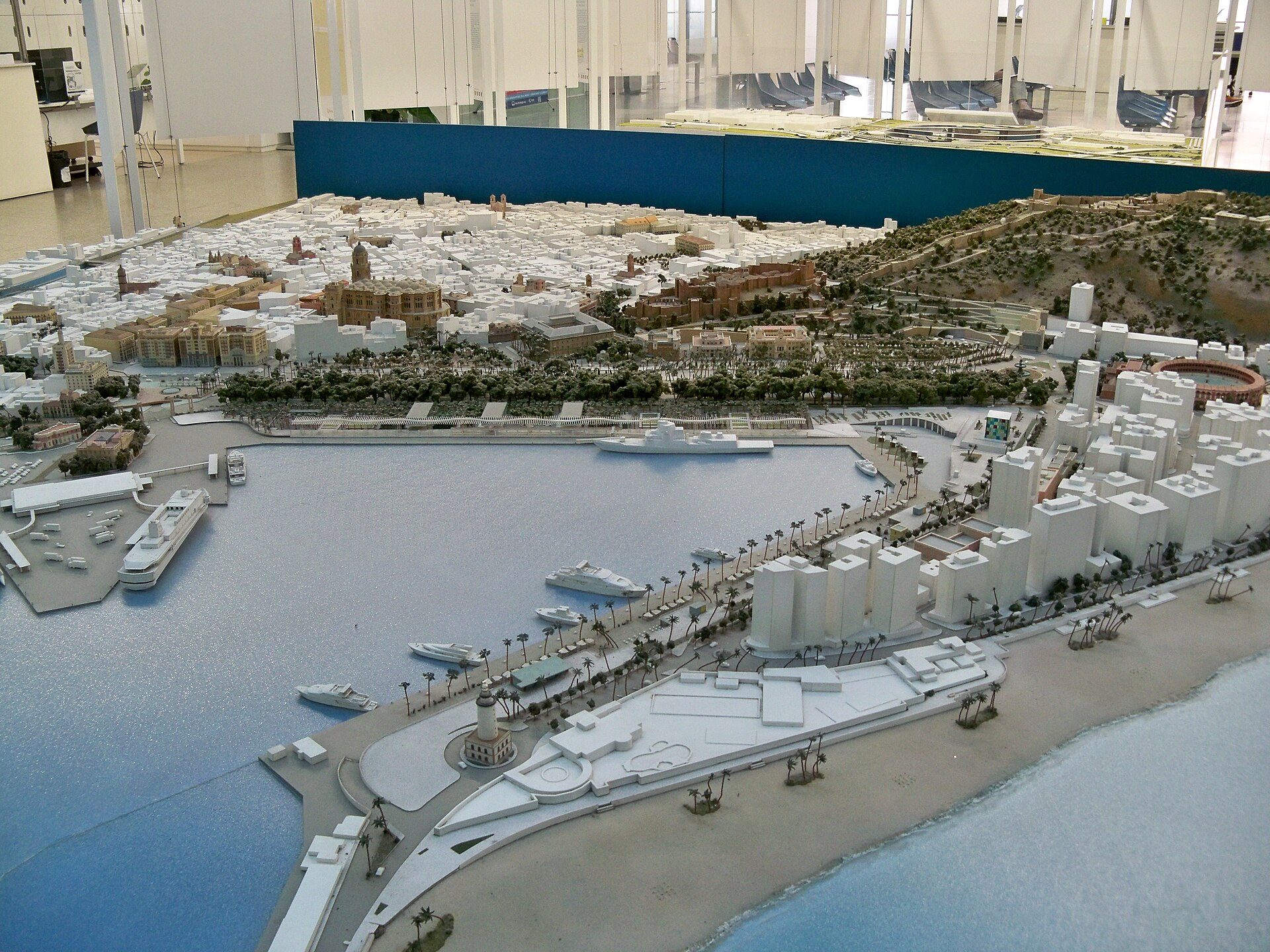 Alt text: Detailed model of a coastal city with waterfront buildings, docks, and a mountainous backdrop.