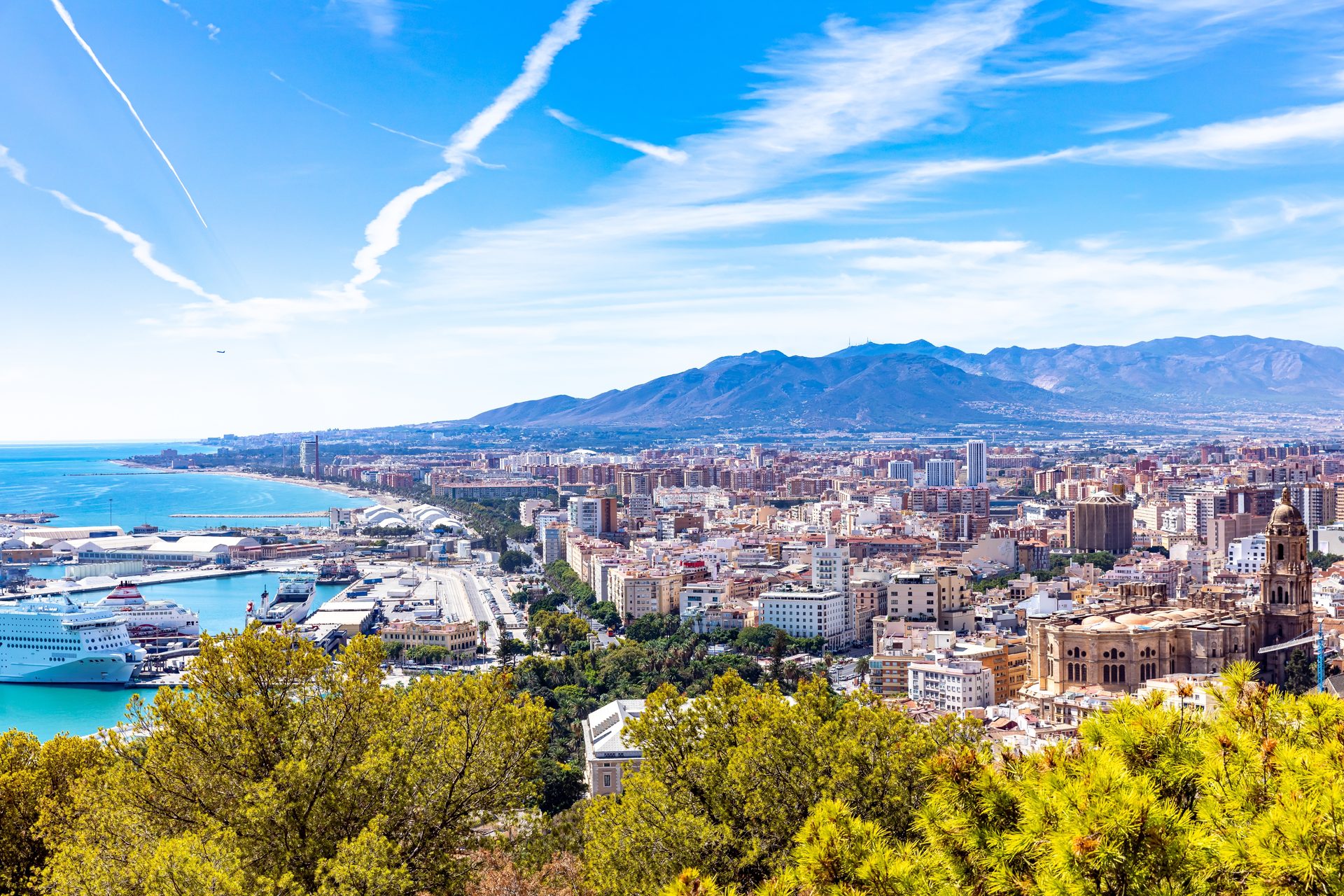 Panoramic city view with mountains, ocean, and cruise ship from balcony.