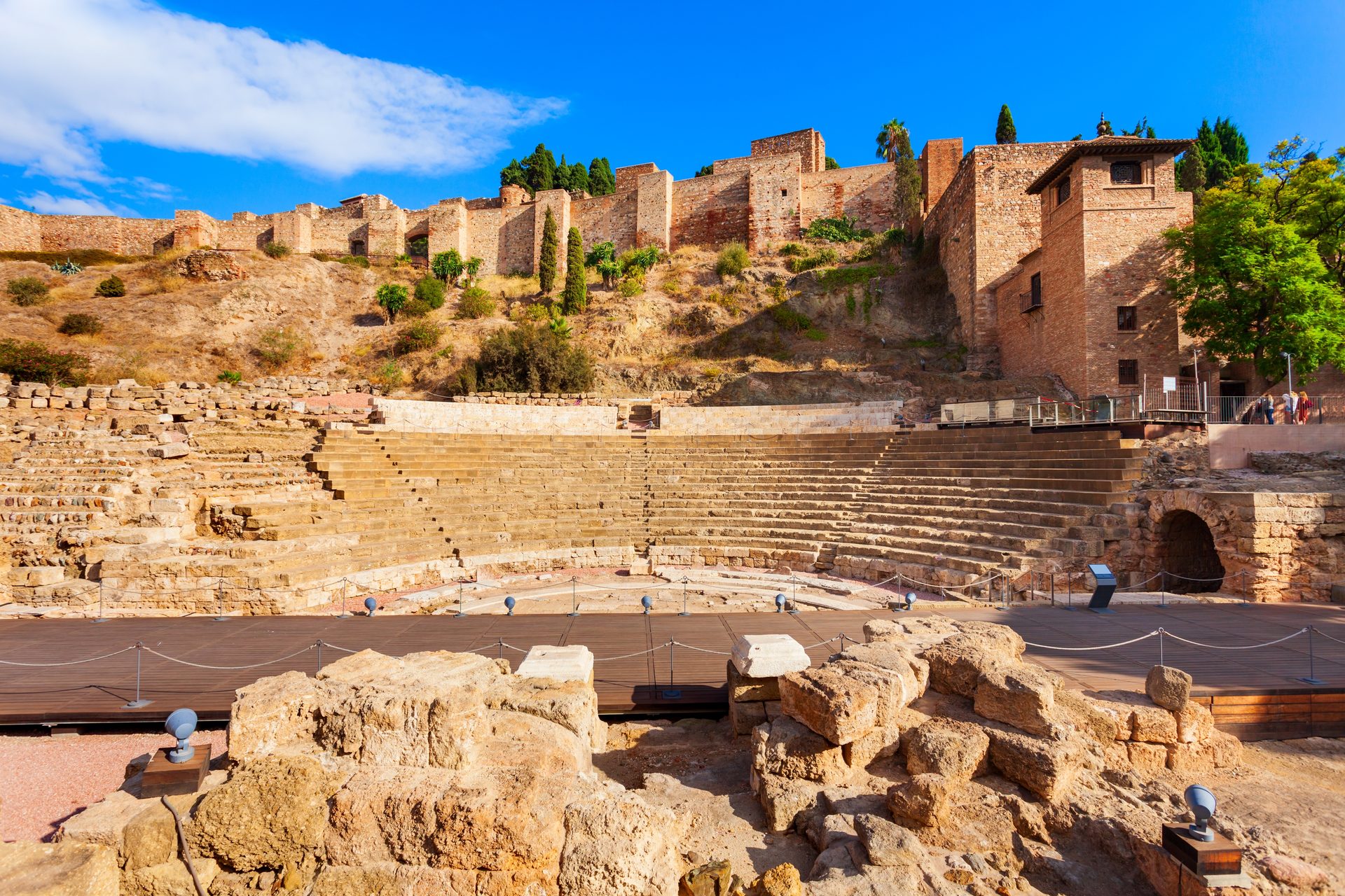 Historic amphitheater with stone seating, scenic hillside view, ancient ruins.
