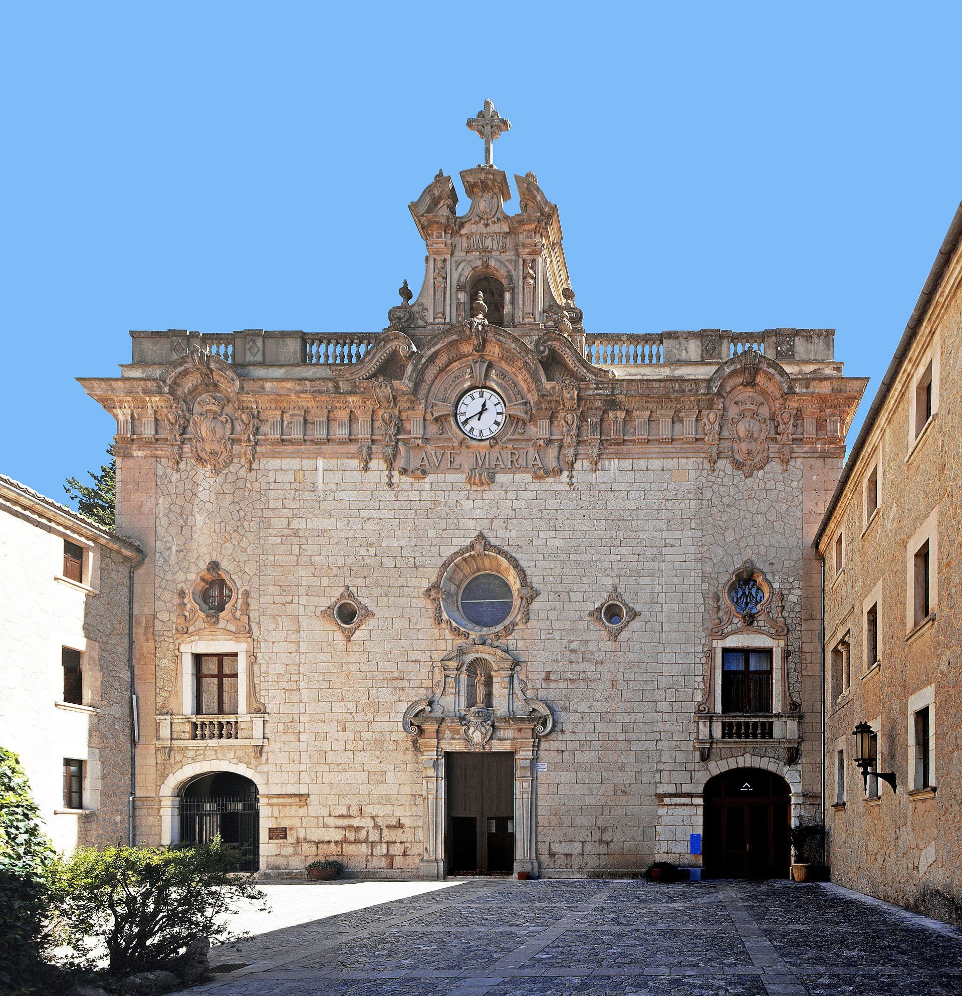 Historic stone building with clock tower, arched windows, and courtyard.