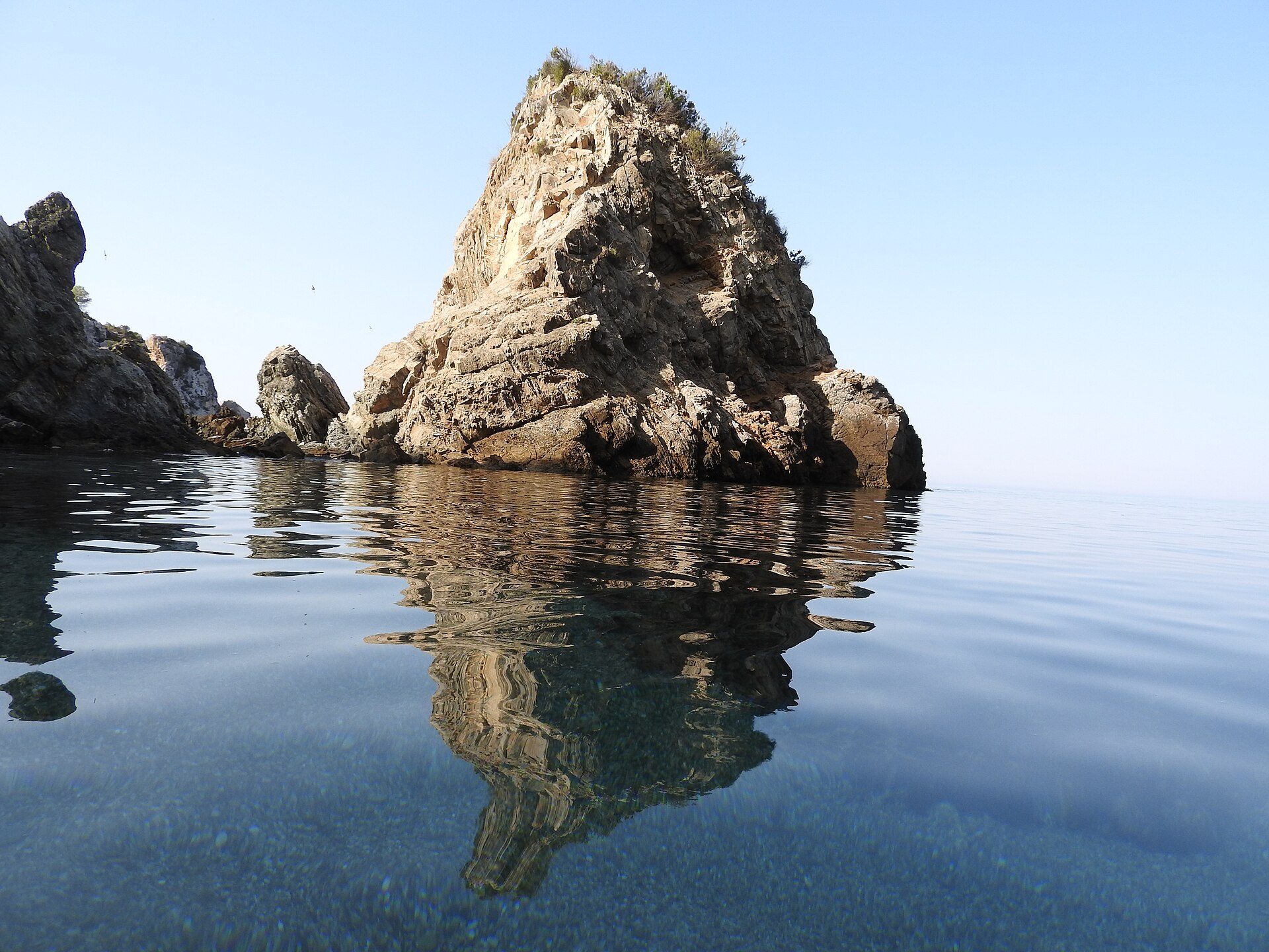 Alt text: Oceanfront room with stunning rock formation and clear blue water view.
