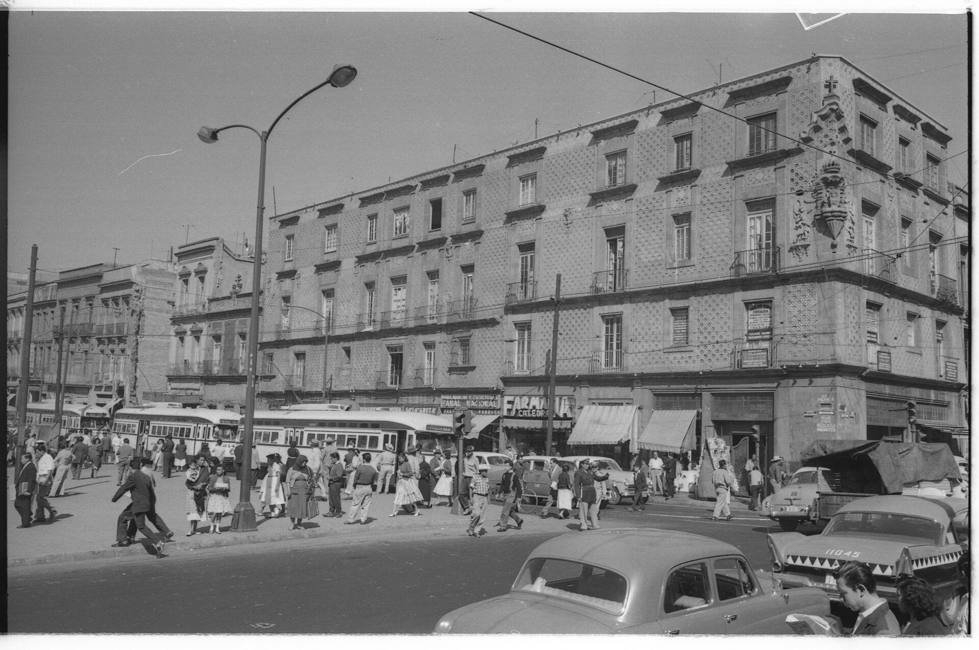 Alt text: Vintage street scene with classic cars, pedestrians, and historic buildings.