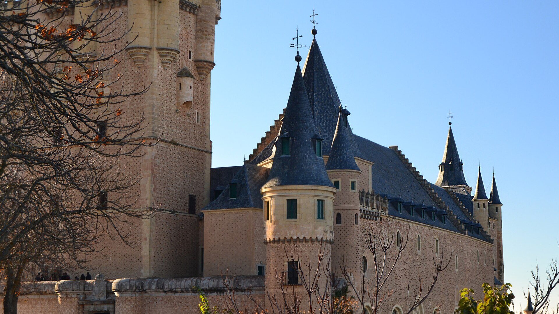 A medieval castle with multiple turrets and a clear blue sky view.