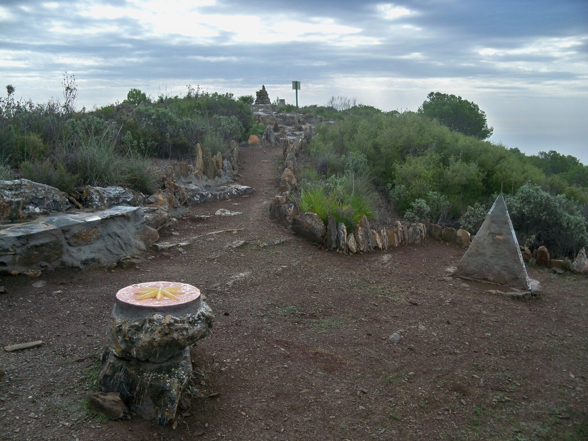 Alt text: Outdoor seating area with a view of the ocean and surrounding greenery.