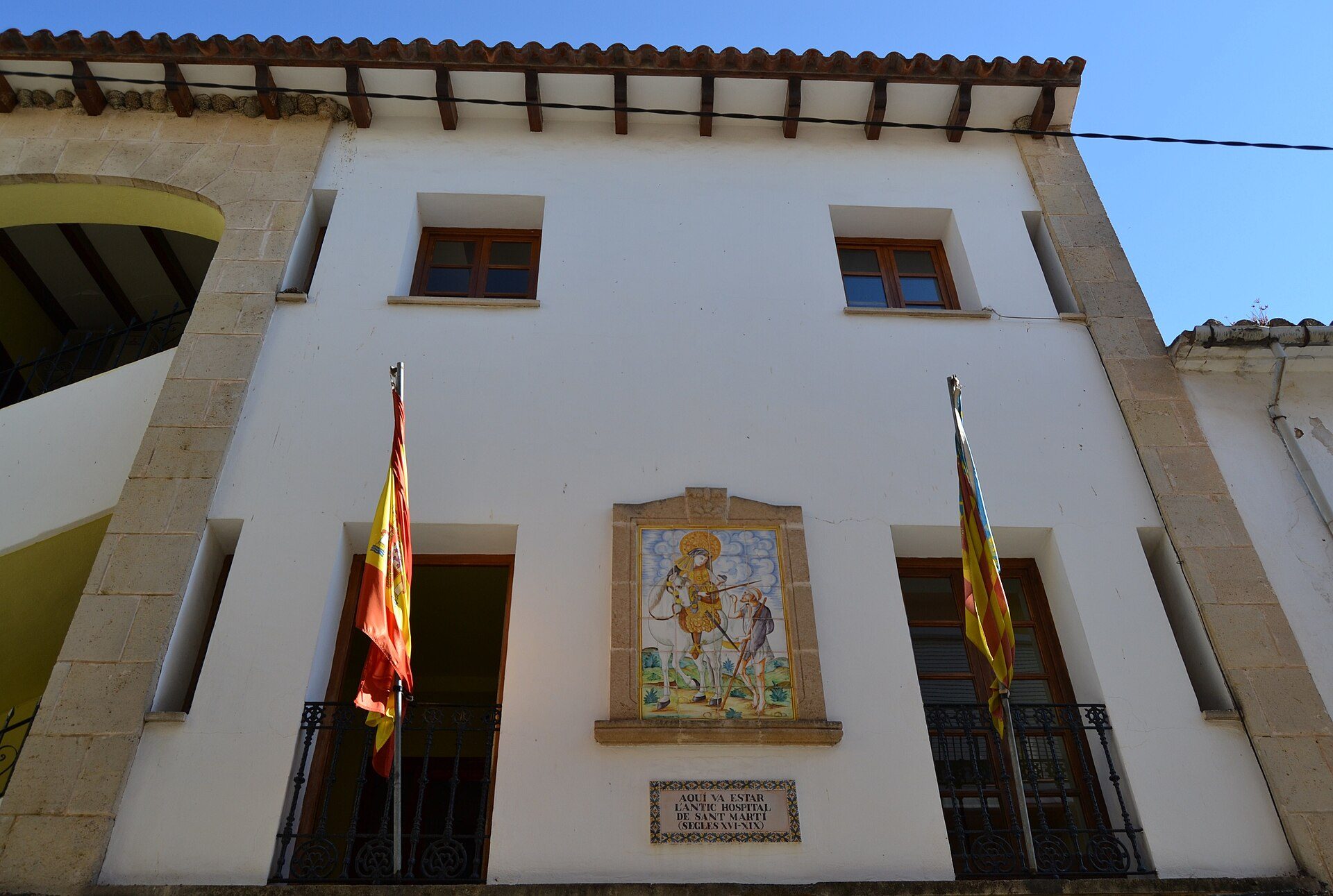 Traditional building with two flags, arched windows, and a mural.