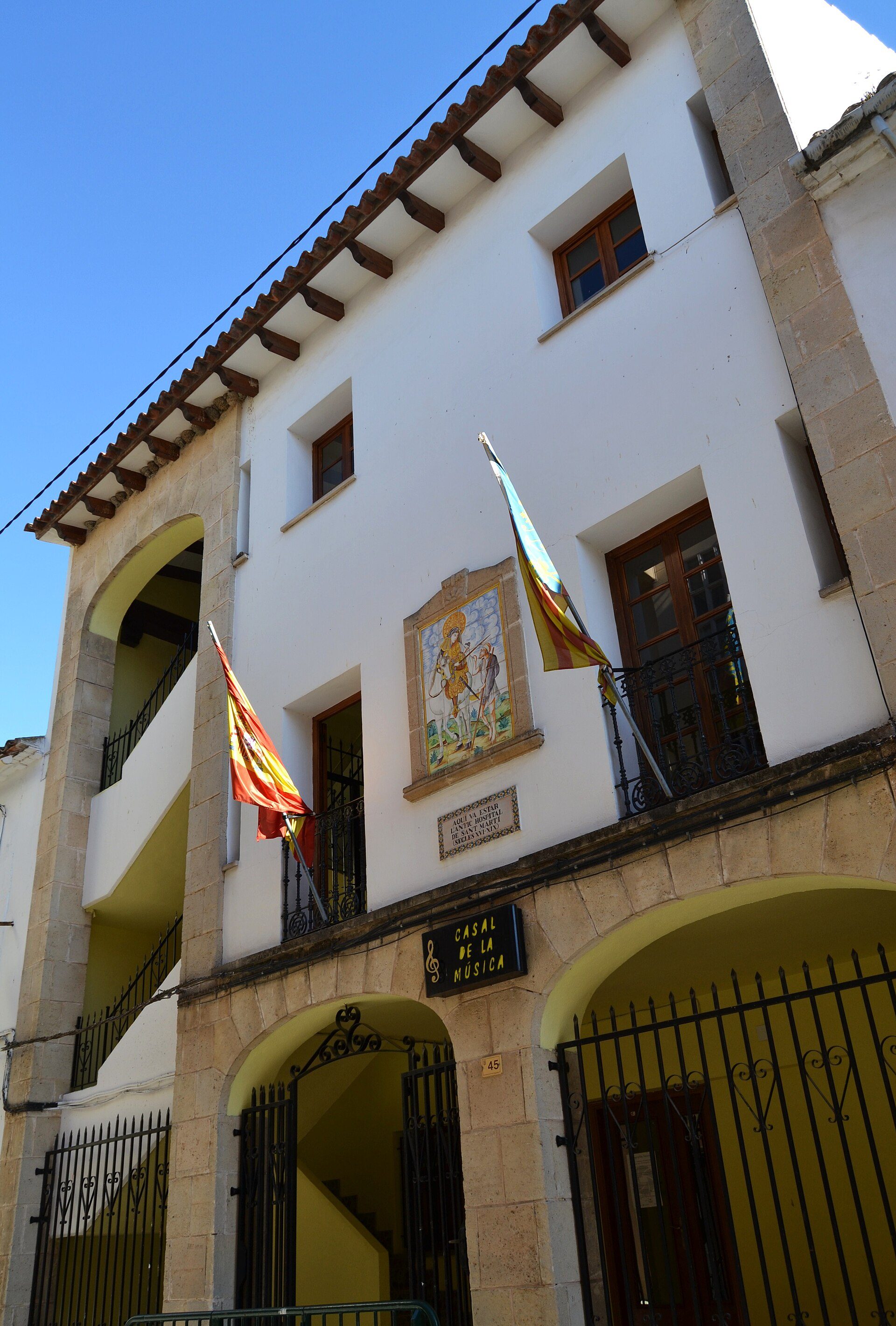 Traditional building with arched windows, balcony, and flags.