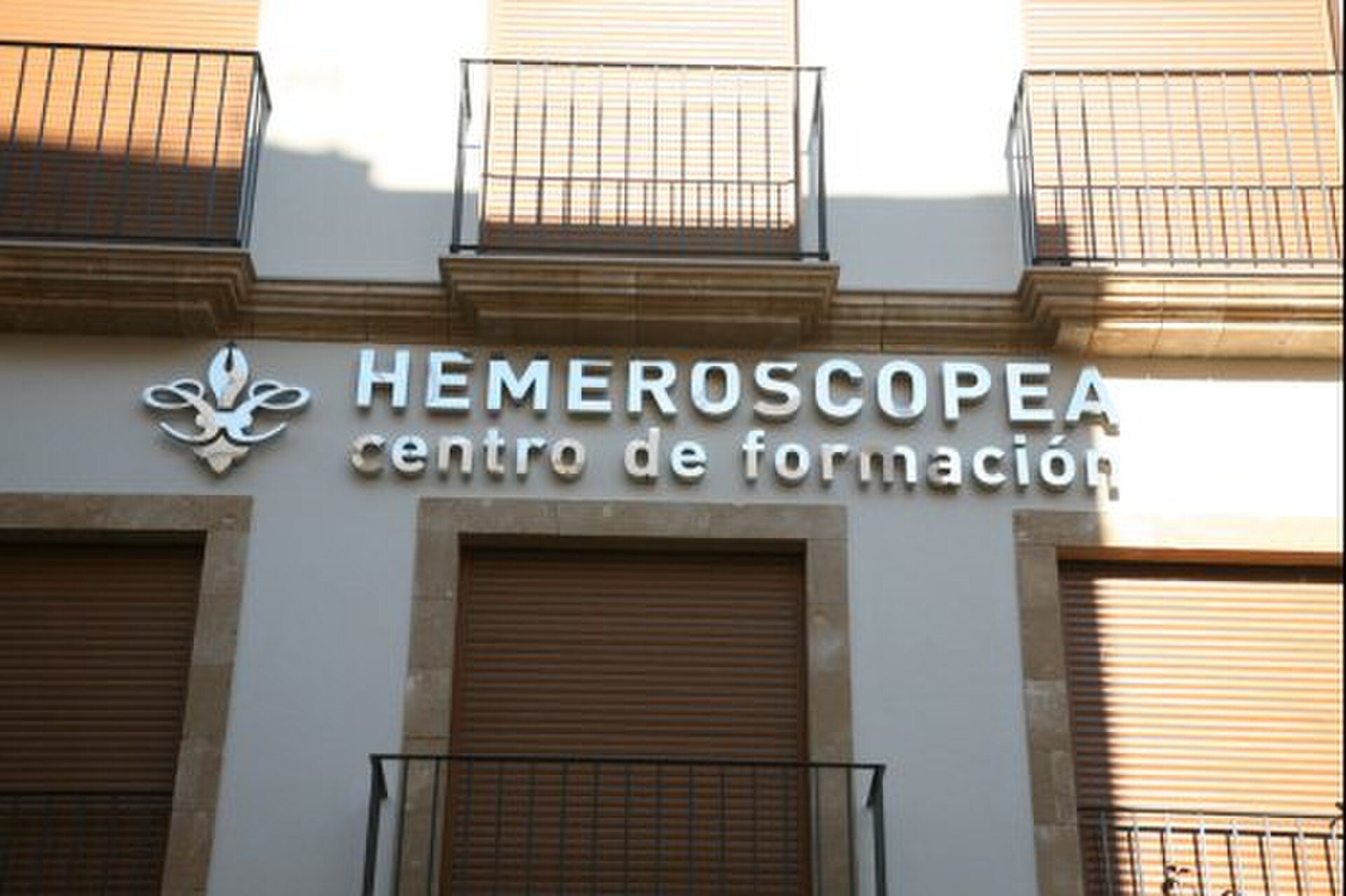 Alt text: "Exterior of HEMEROSCOPEA training center with balconies and signage.
