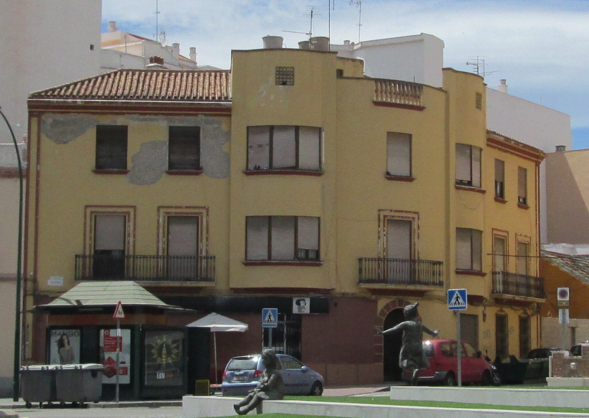 Yellow building with balconies, street view, urban setting.