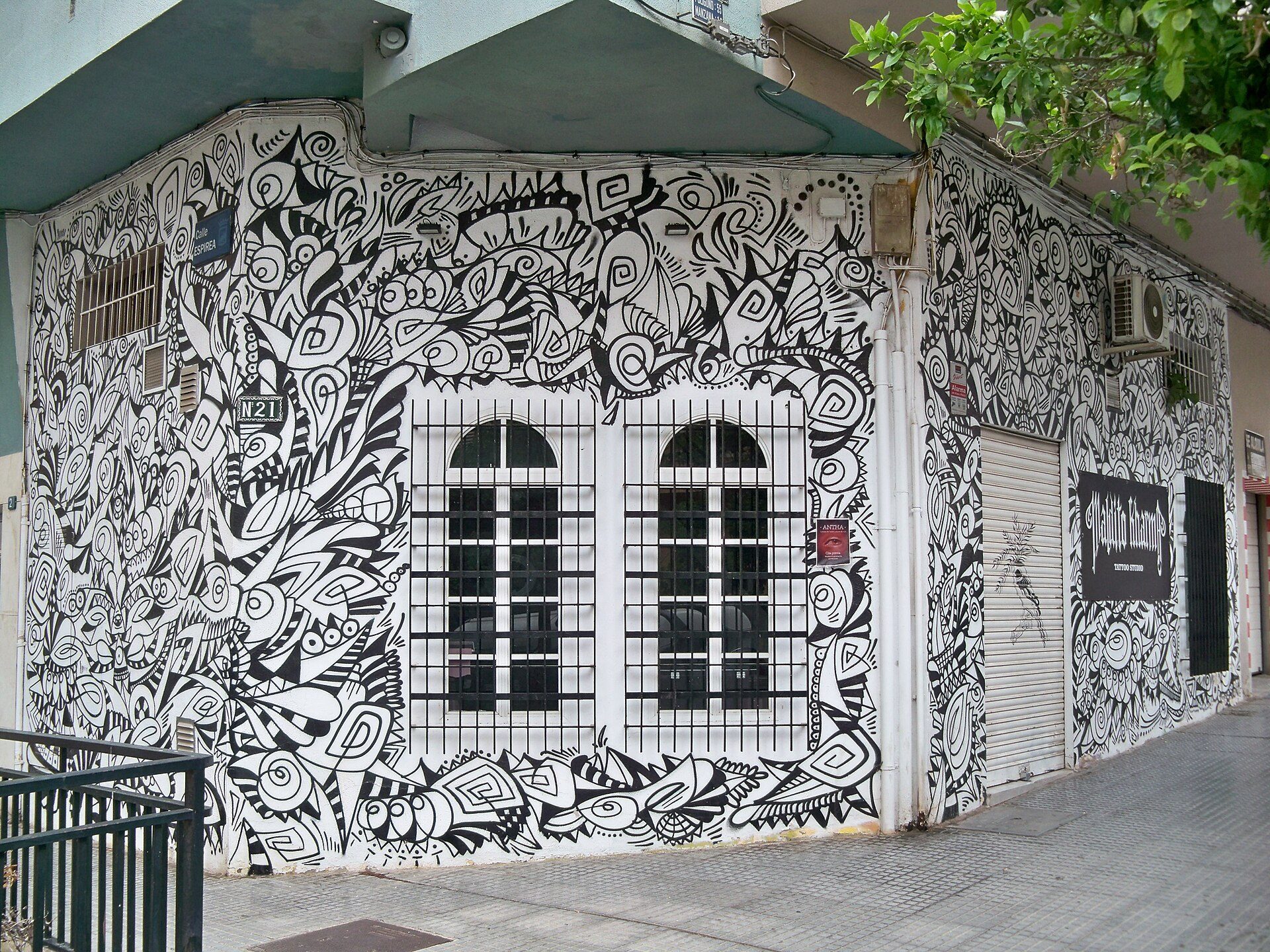 A street view of a building with intricate black and white mural art on the exterior.