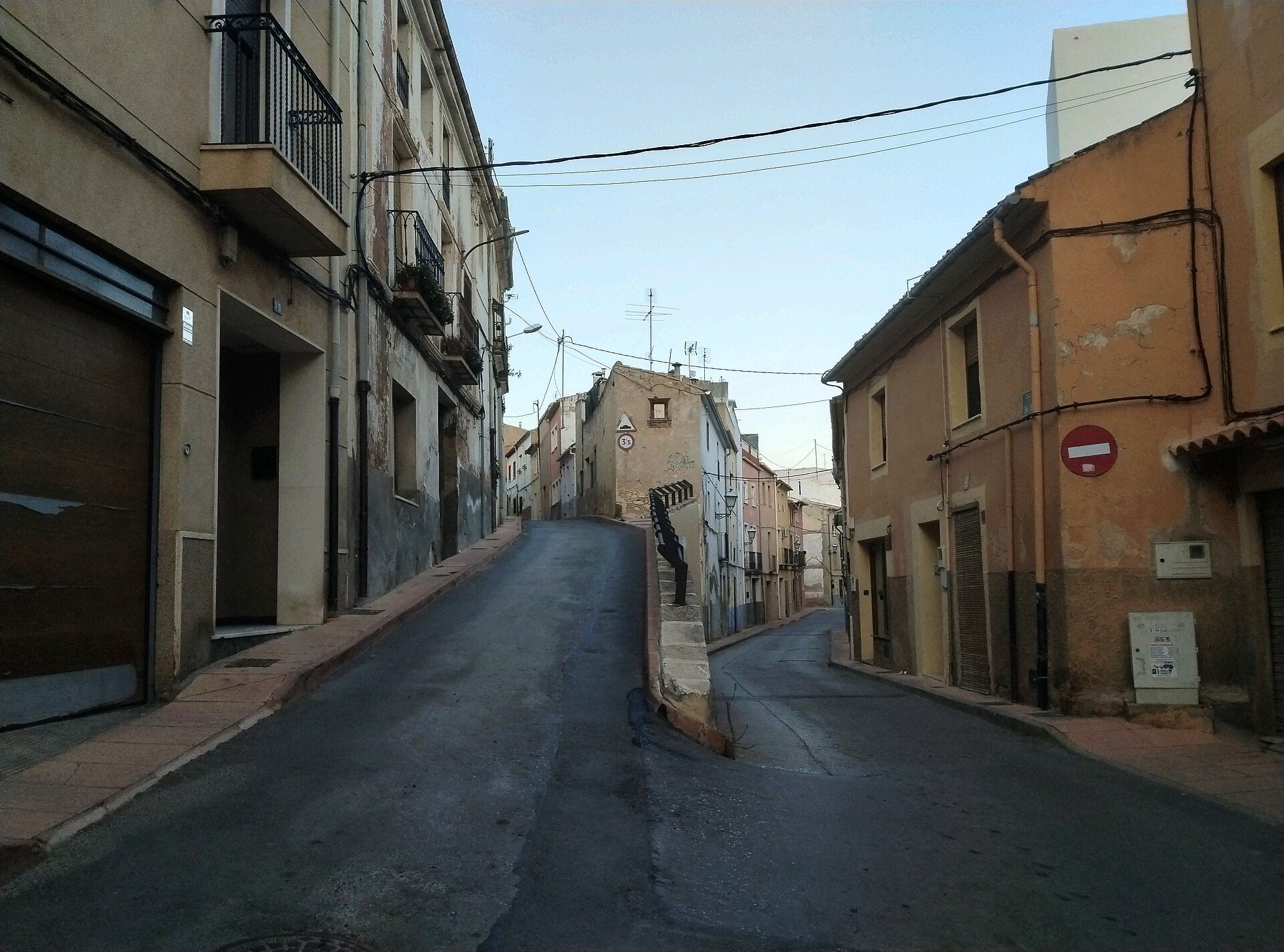 A narrow street in a quaint town with old buildings and a clear blue sky.