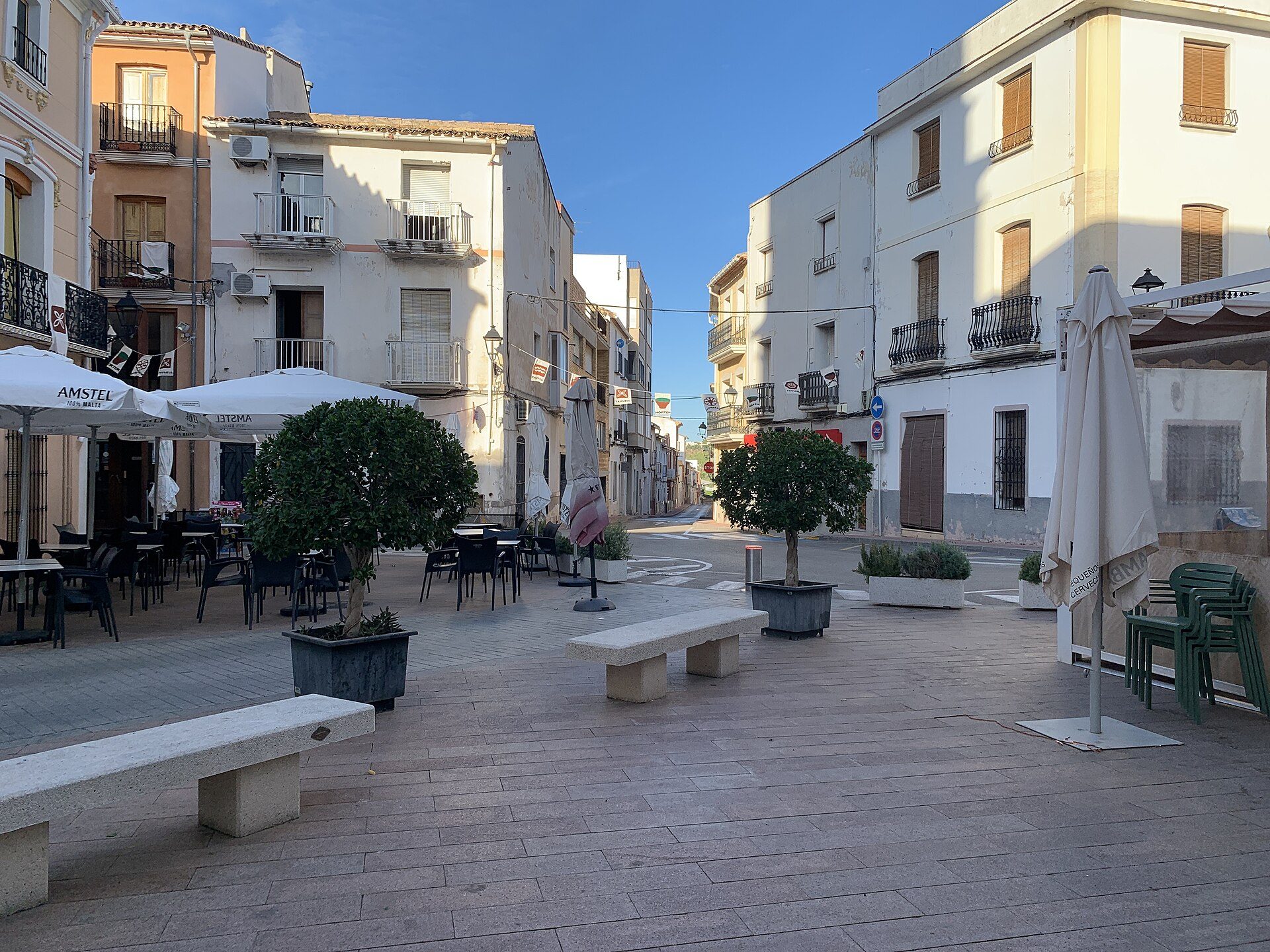 Alt text: Outdoor seating area with tables, chairs, and umbrellas in a European-style square.