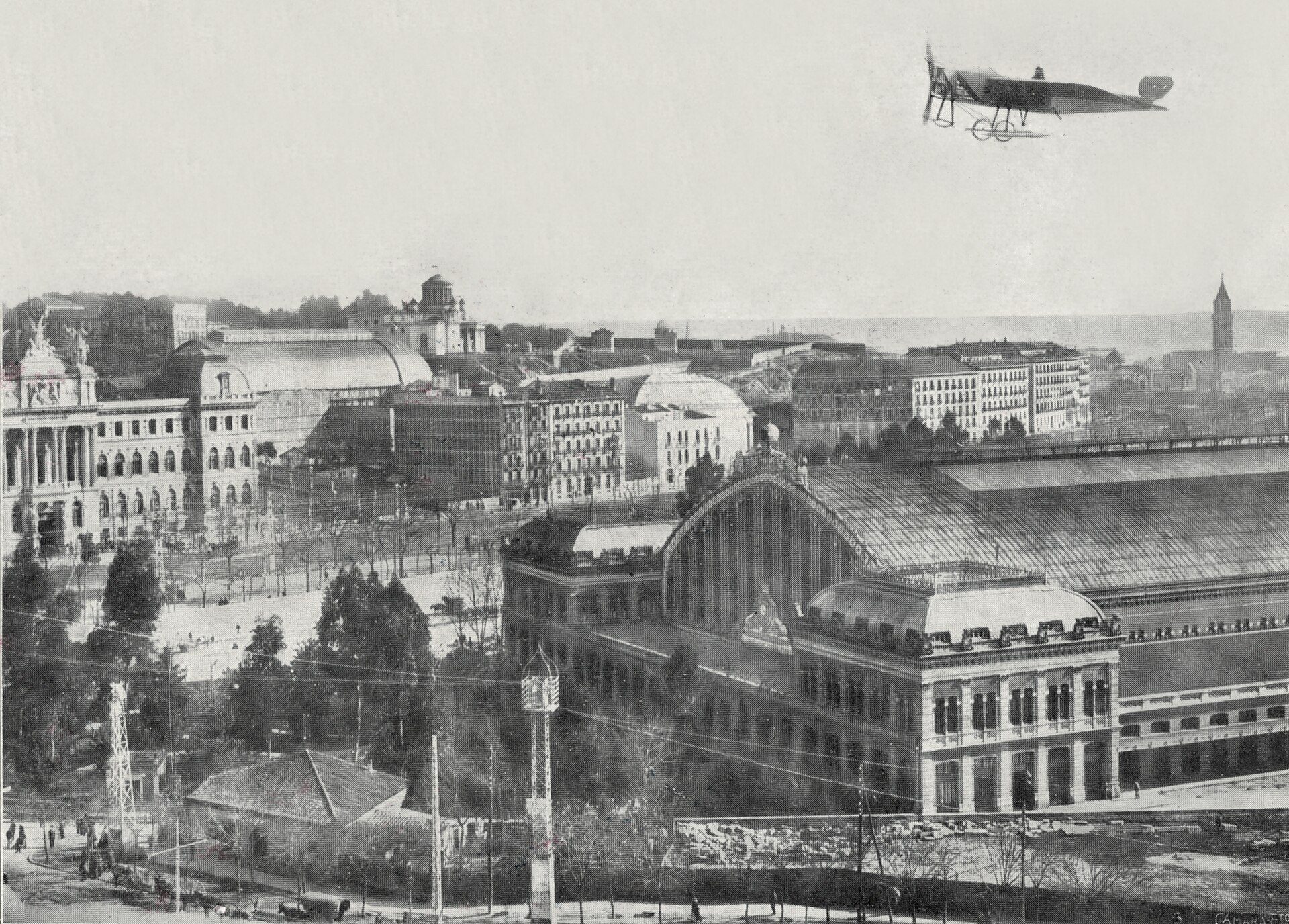 Historic cityscape with large building and early airplane in flight.