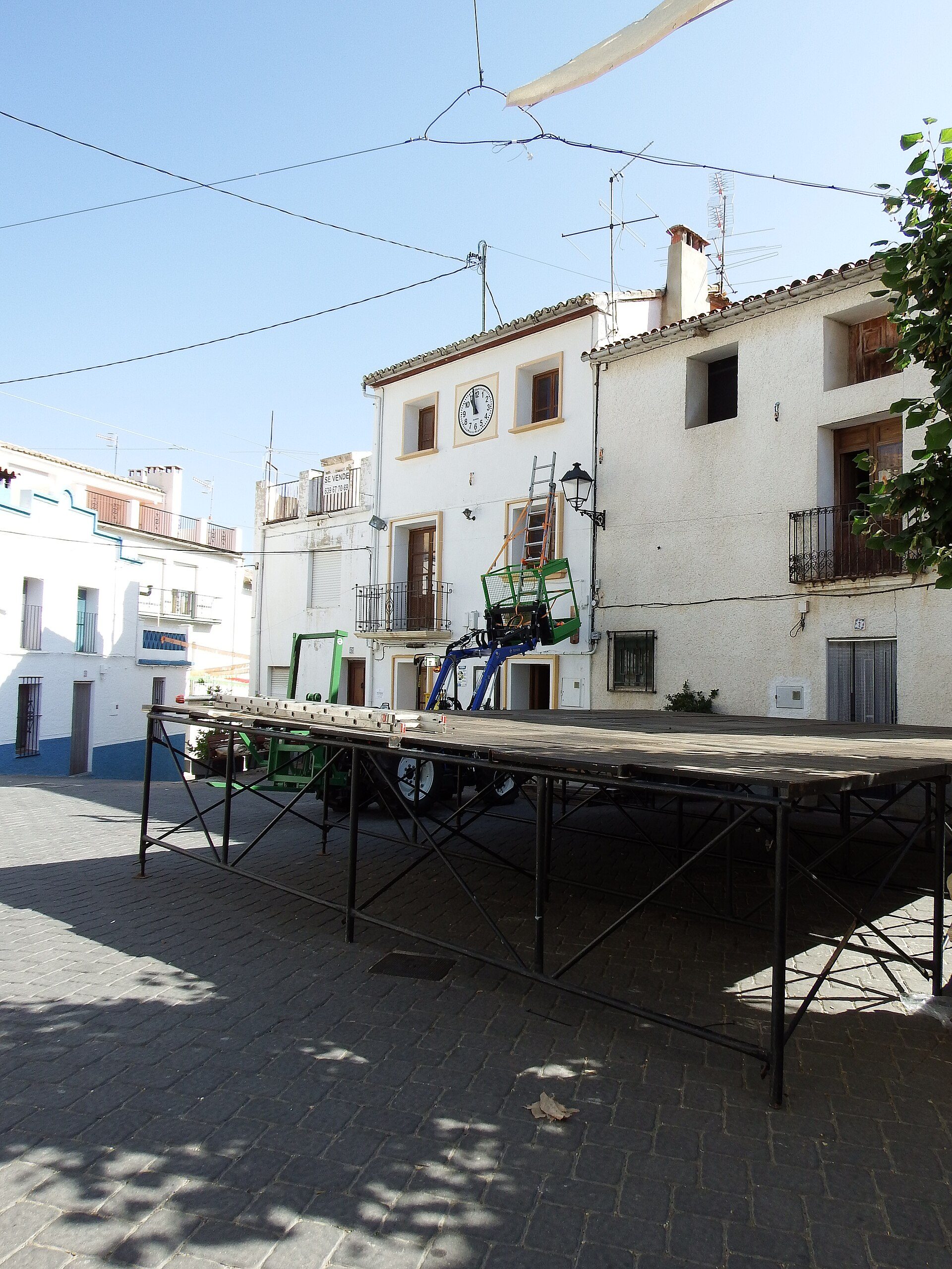 Outdoor stage with a clock tower view, featuring a large screen and seating area.