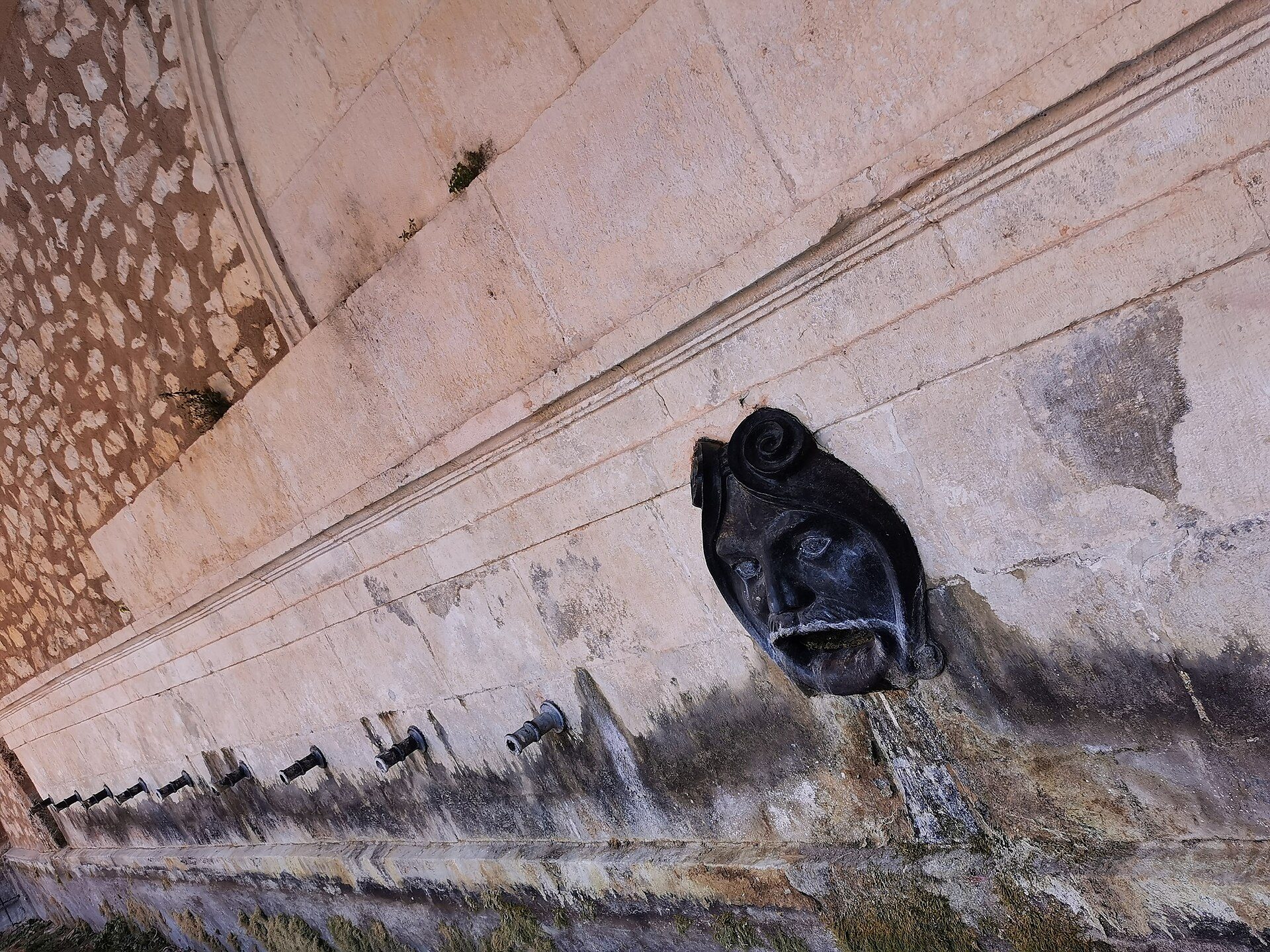Alt text: Interior view of a room with a stone wall, decorative carvings, and a patterned ceiling.
