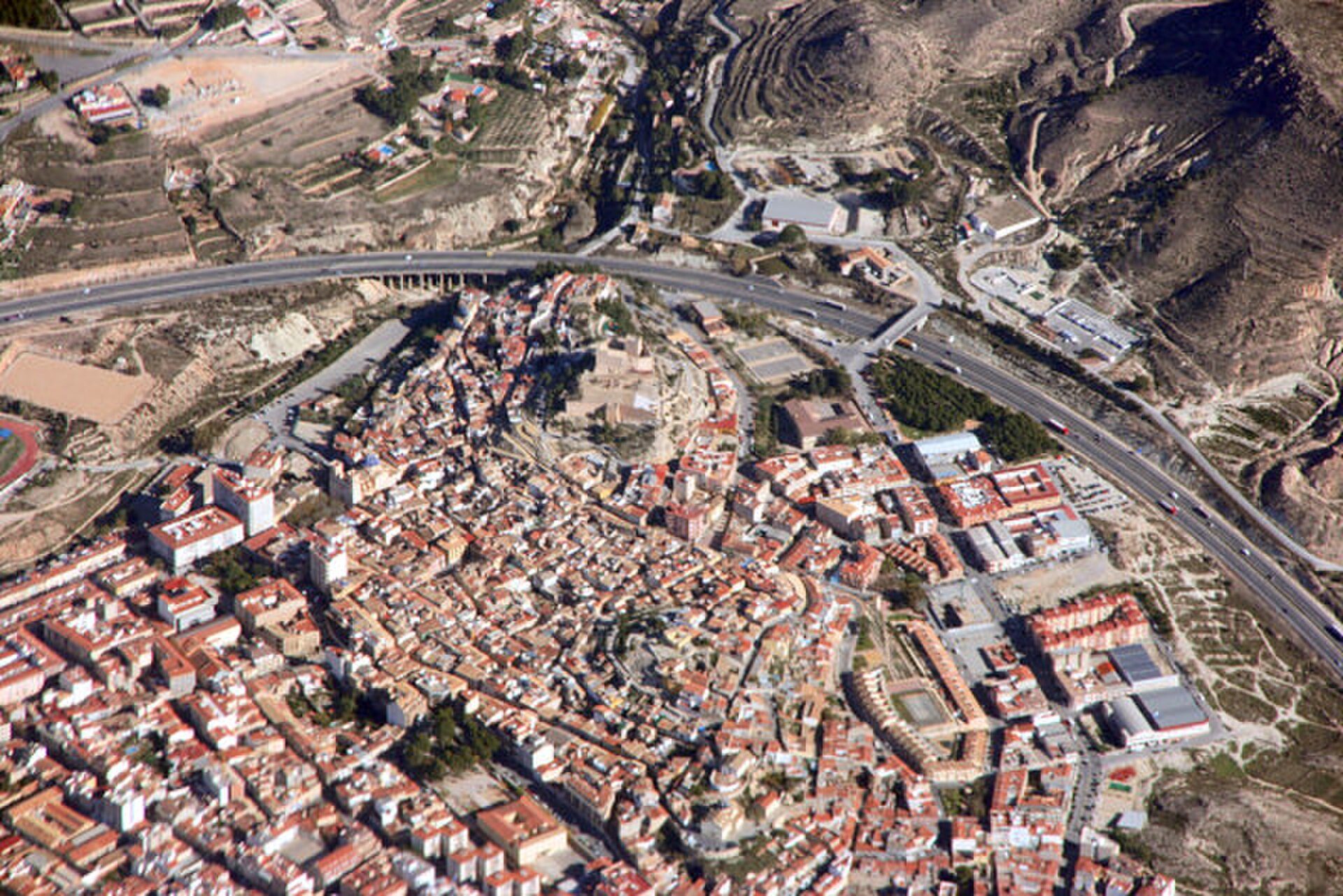 Aerial view of a small town with red-roofed buildings and a highway.