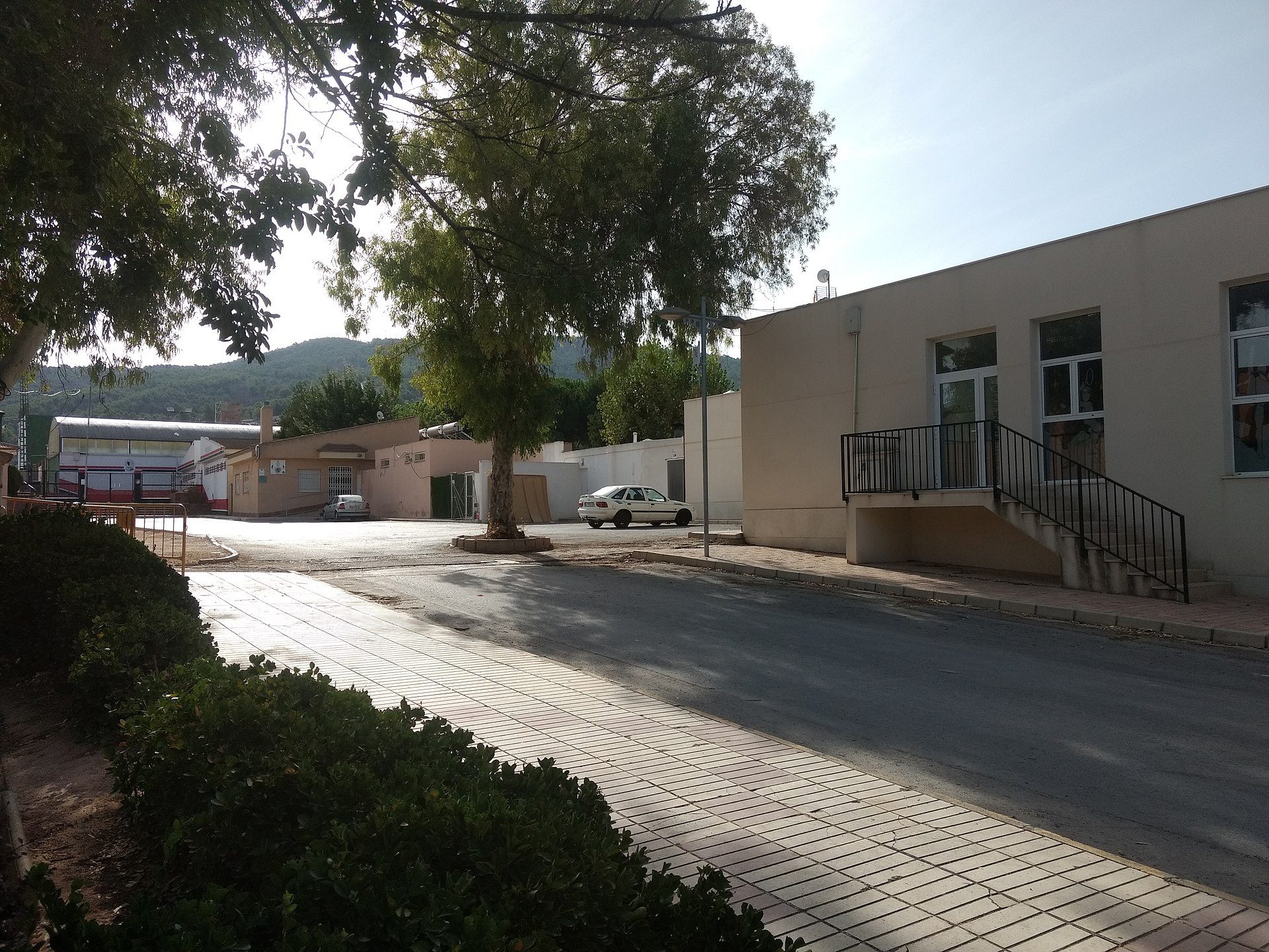 Alt text: Single-story office building with large windows, paved parking area, and surrounding greenery.