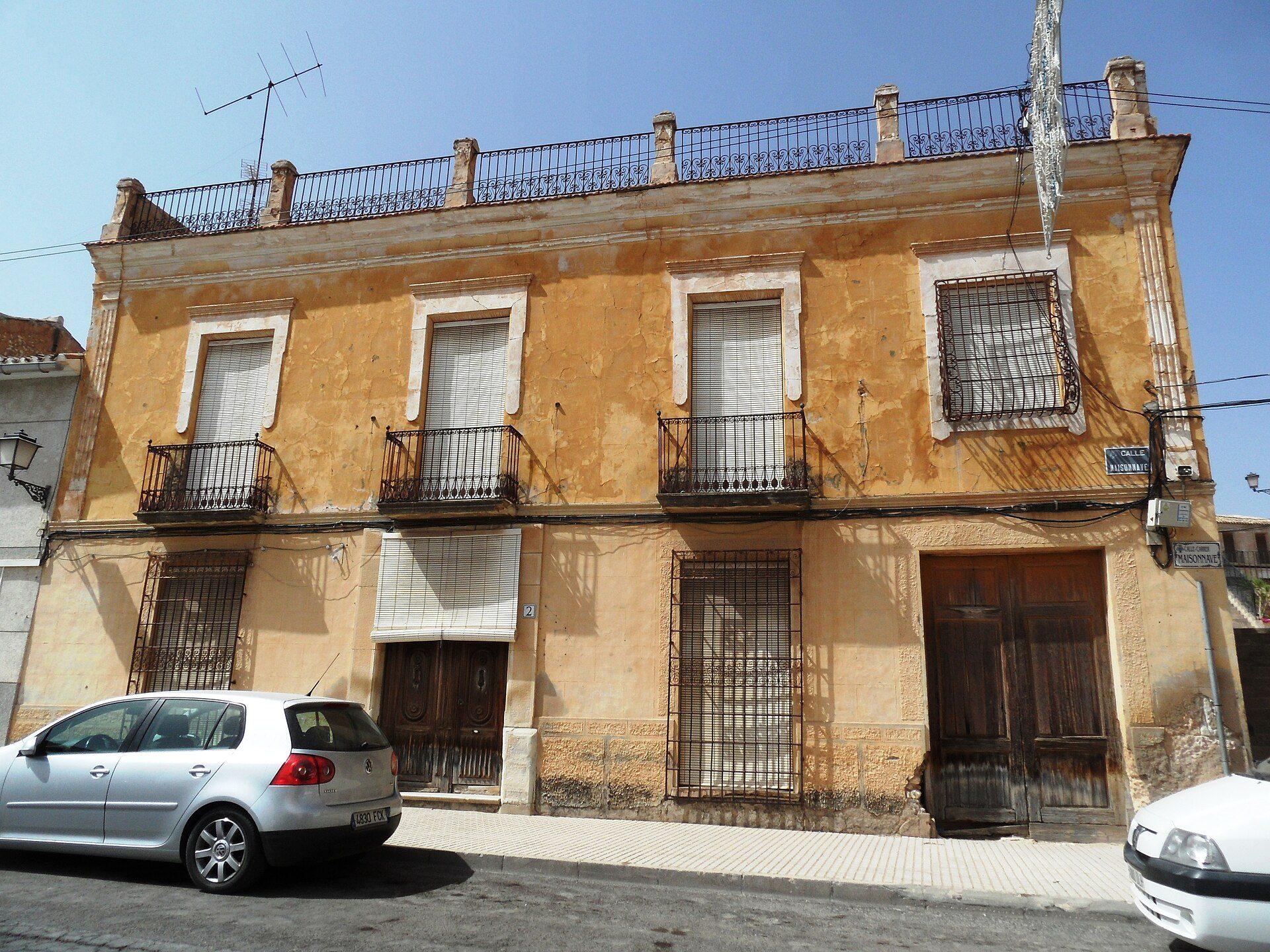 Two-story building with balconies, large windows, and a street view.