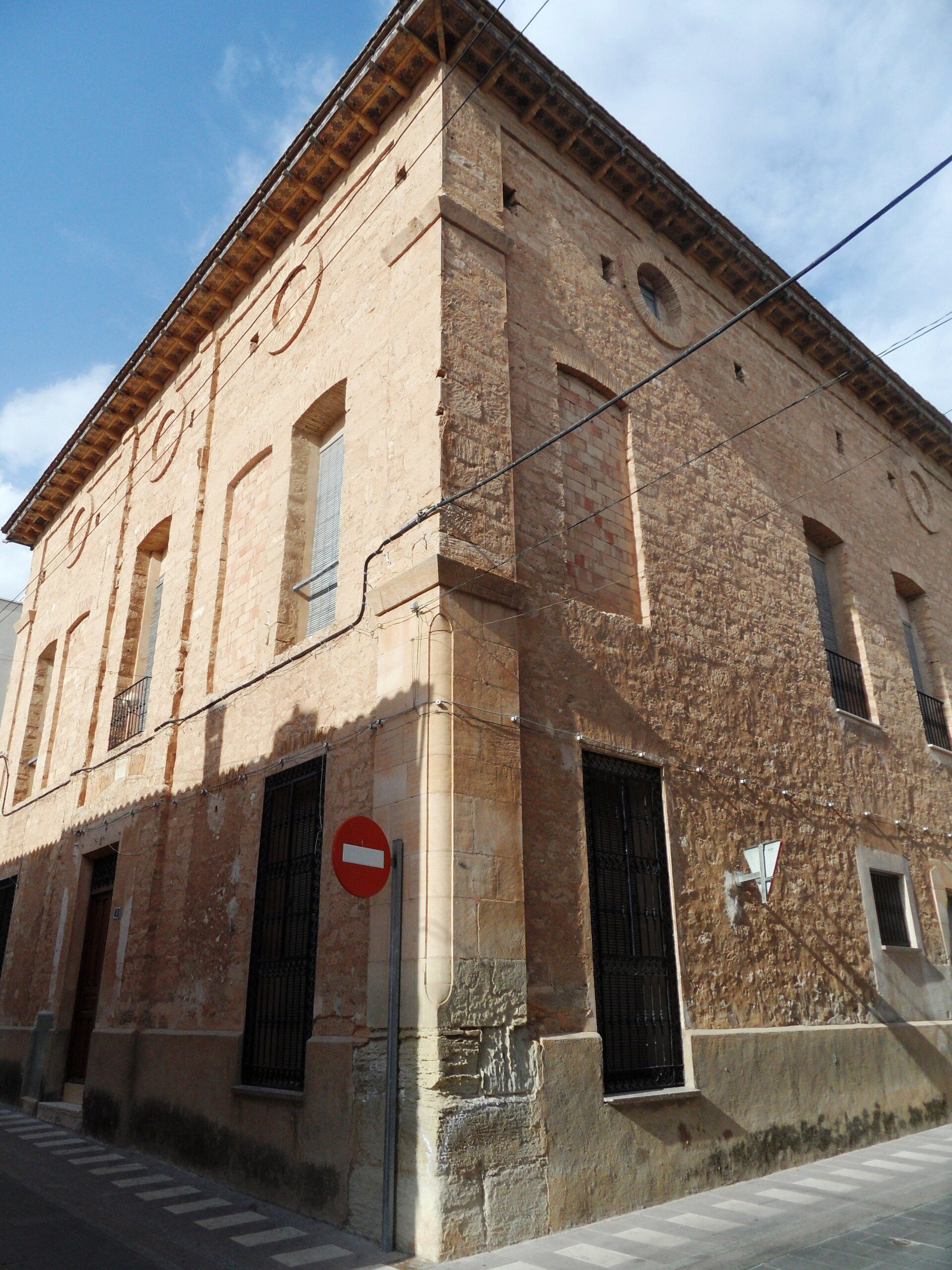 A historic building with arched windows, brick facade, and a no entry sign.