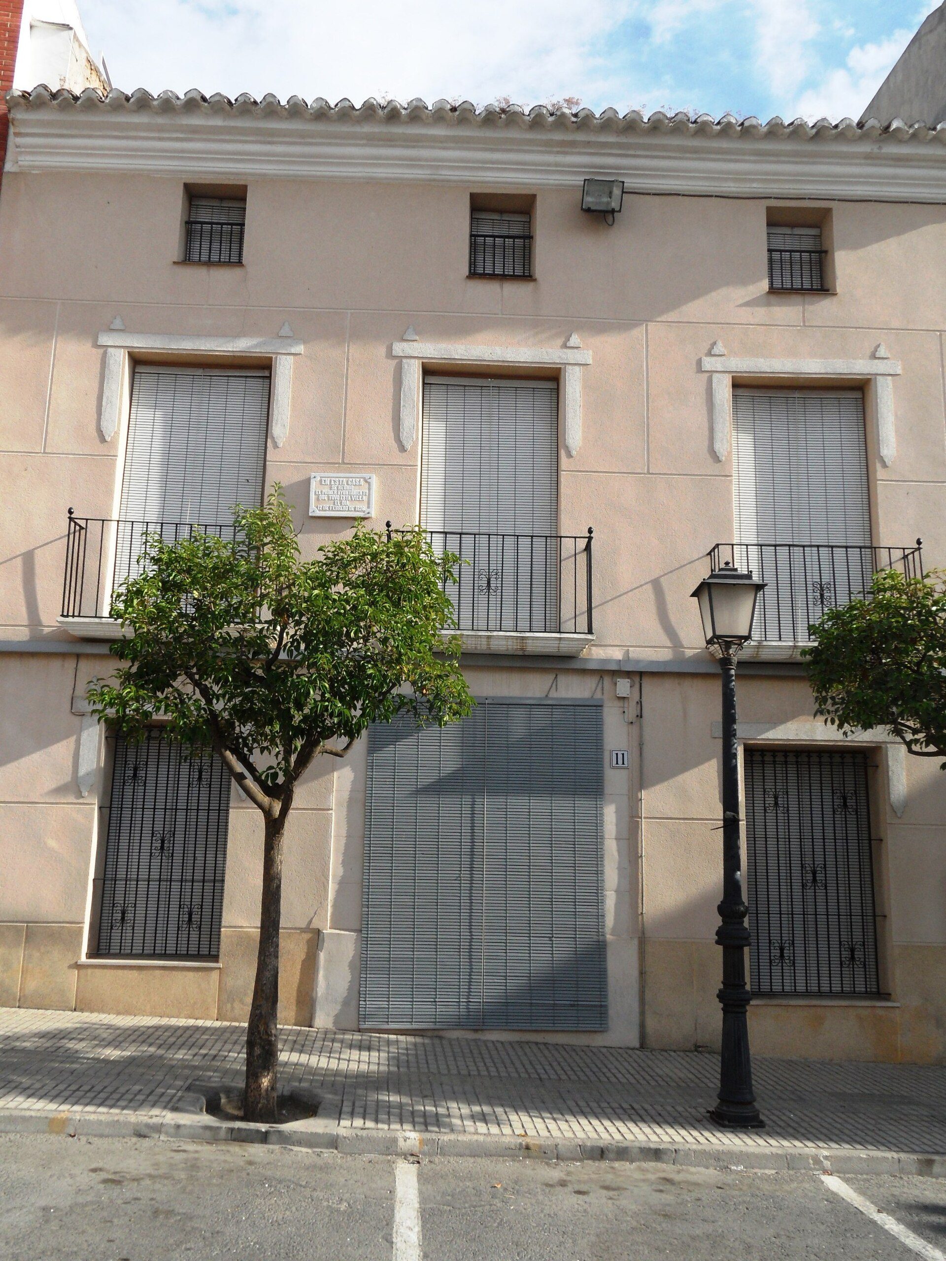 Two-story building with balconies, large windows, and a garage.