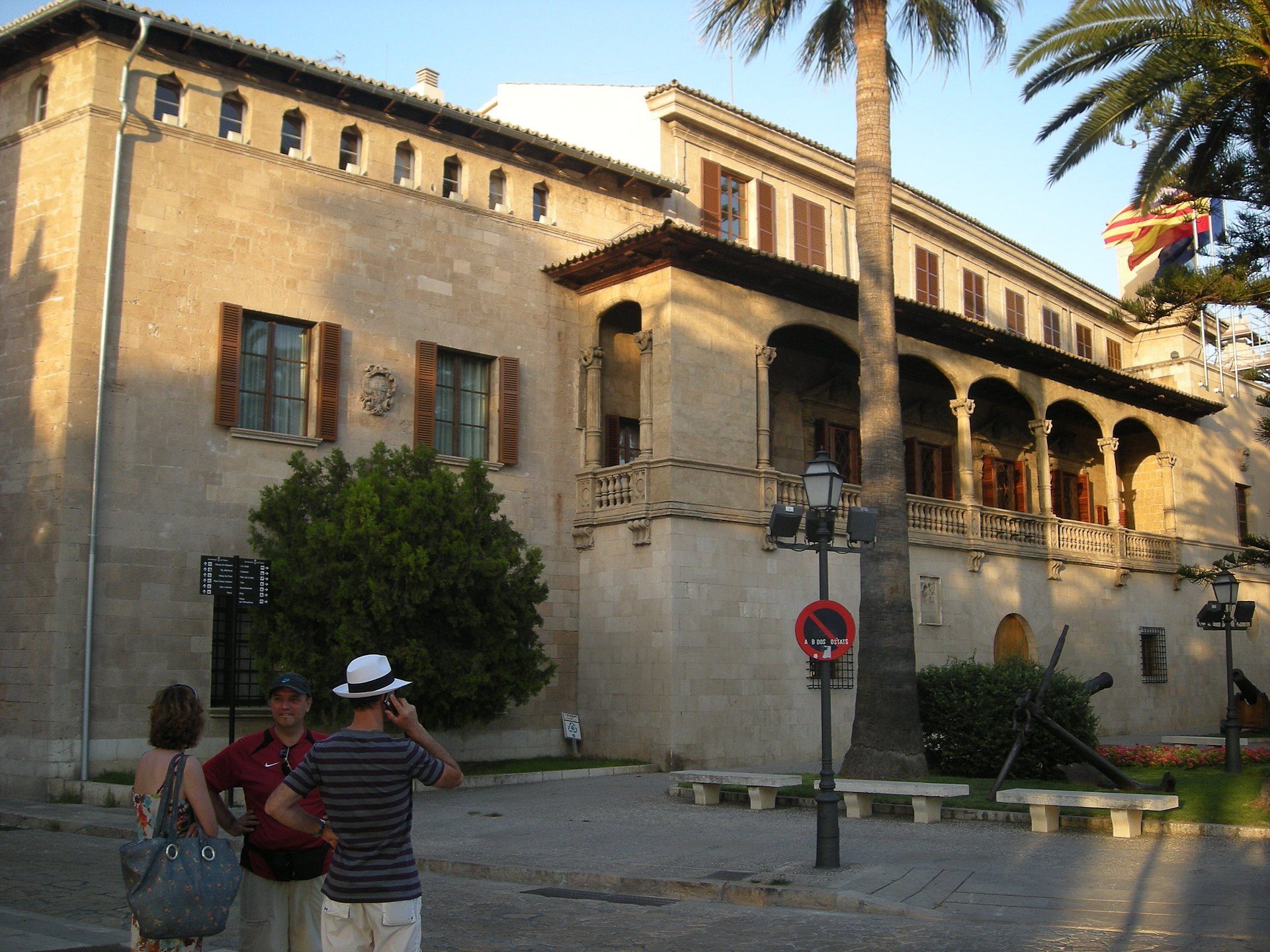 Alt text: Historic building with arched windows, palm tree, and a no entry sign.