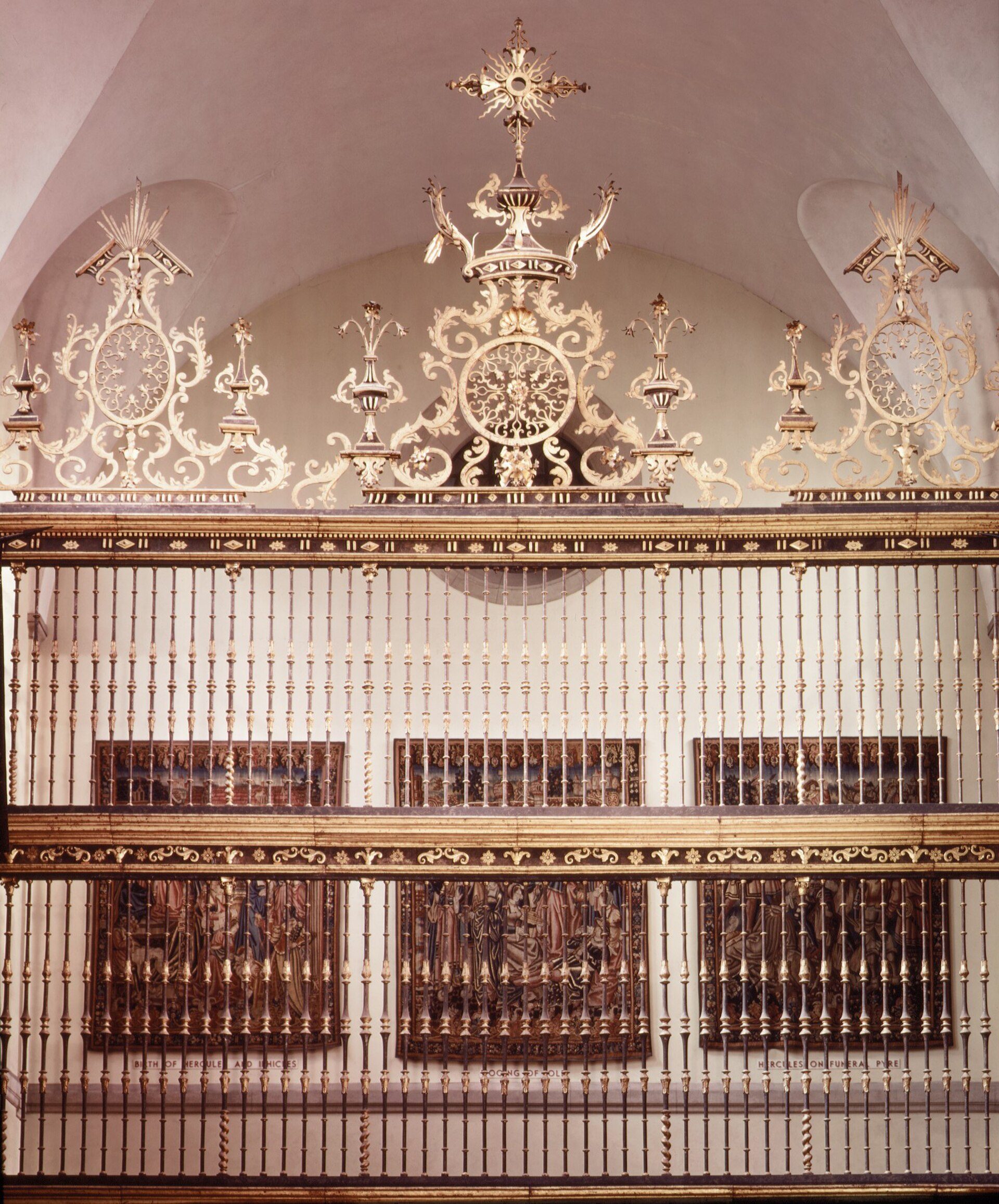 Elegant chandelier-adorned room with ornate gold railings and framed artwork.