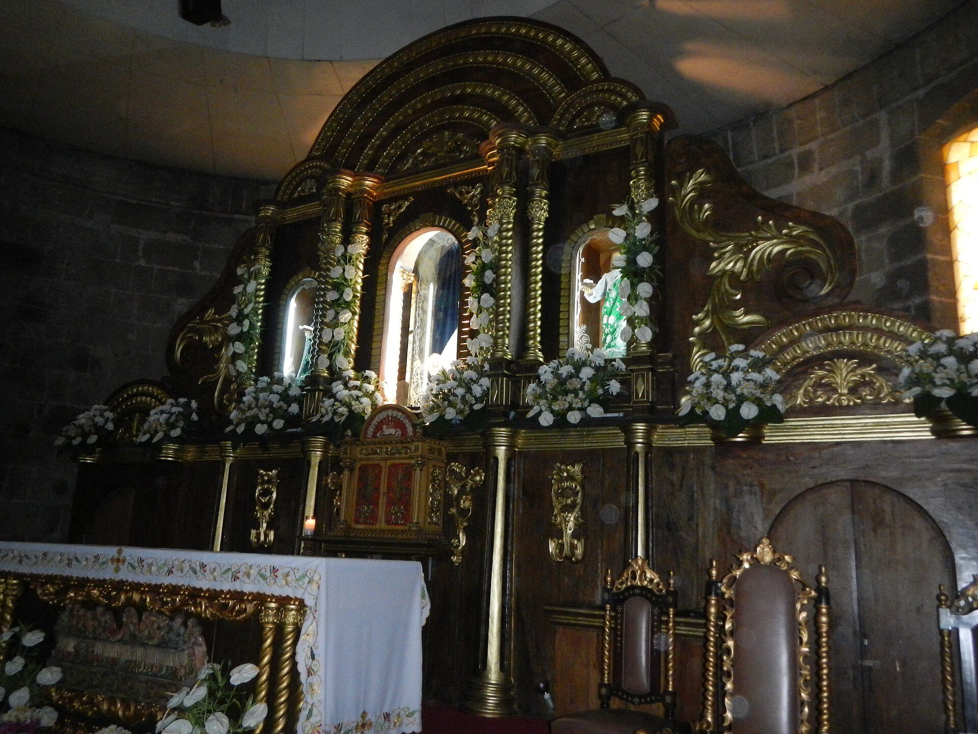 Altar in a church with ornate decorations, religious icons, and floral arrangements.