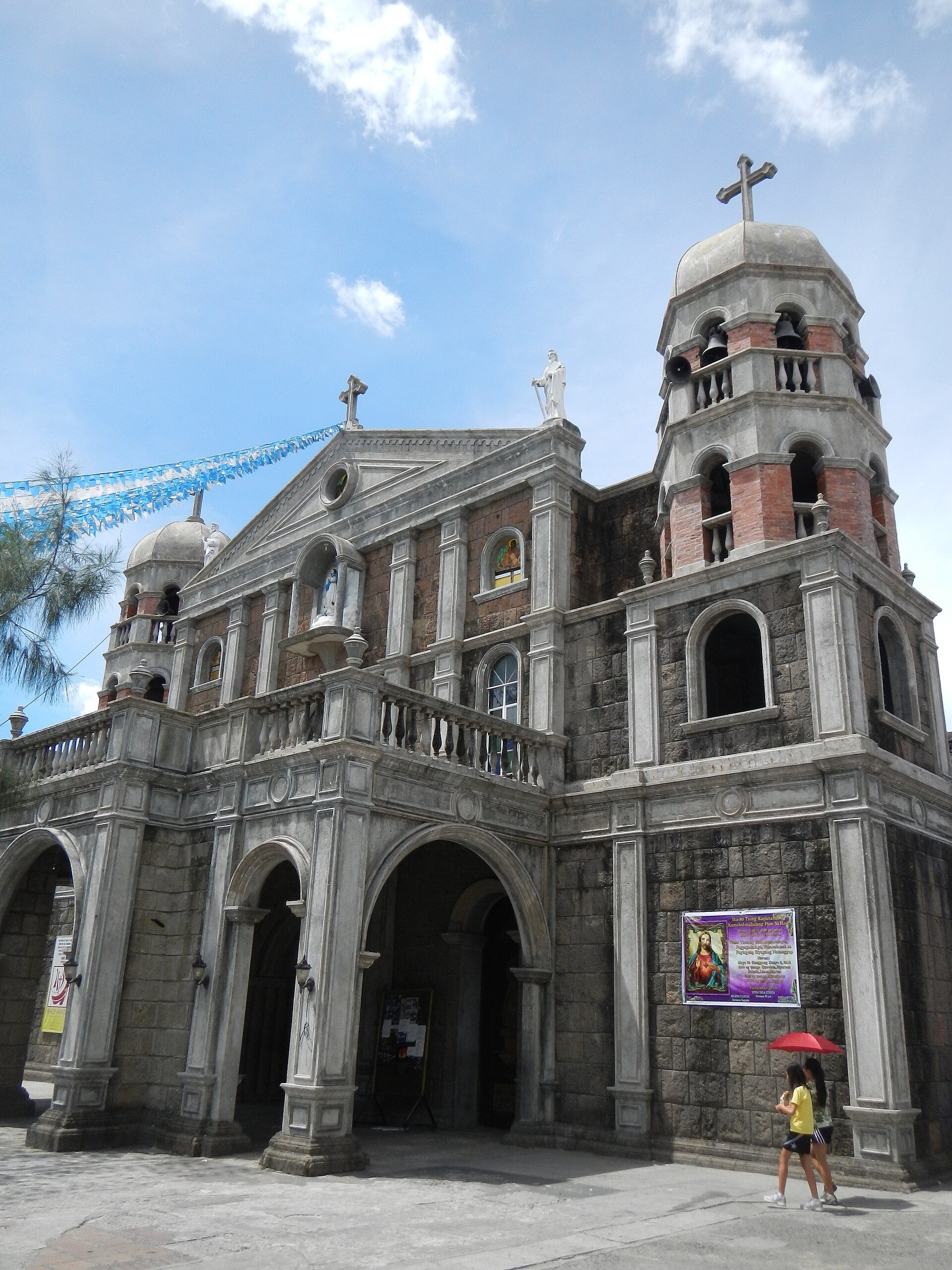 Alt text: Historic church with arched entrances, bell towers, and a cross on top.