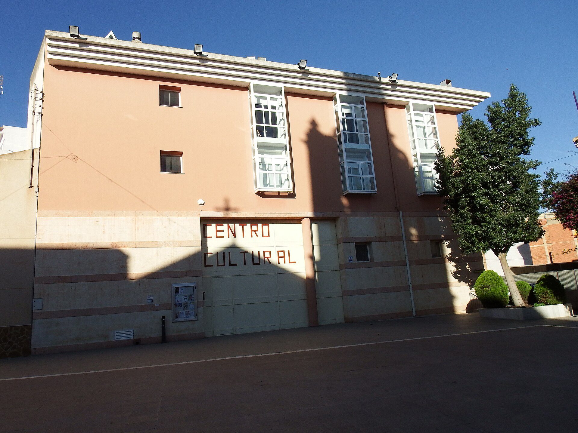 Alt text: Two-story building with large windows, "CENTRO CULTURAL" sign, and a tree.