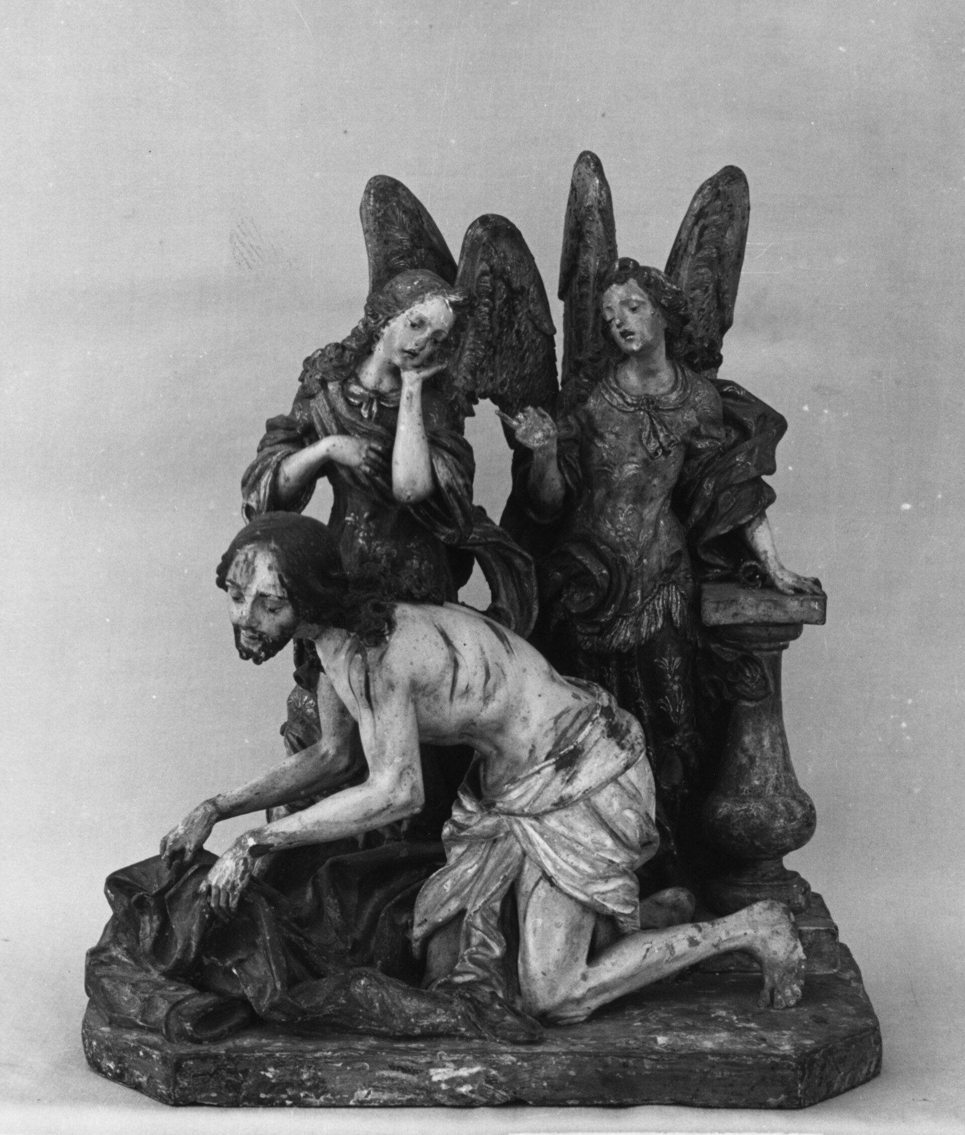 Alt text: Black and white sculpture depicting a kneeling figure with angels.