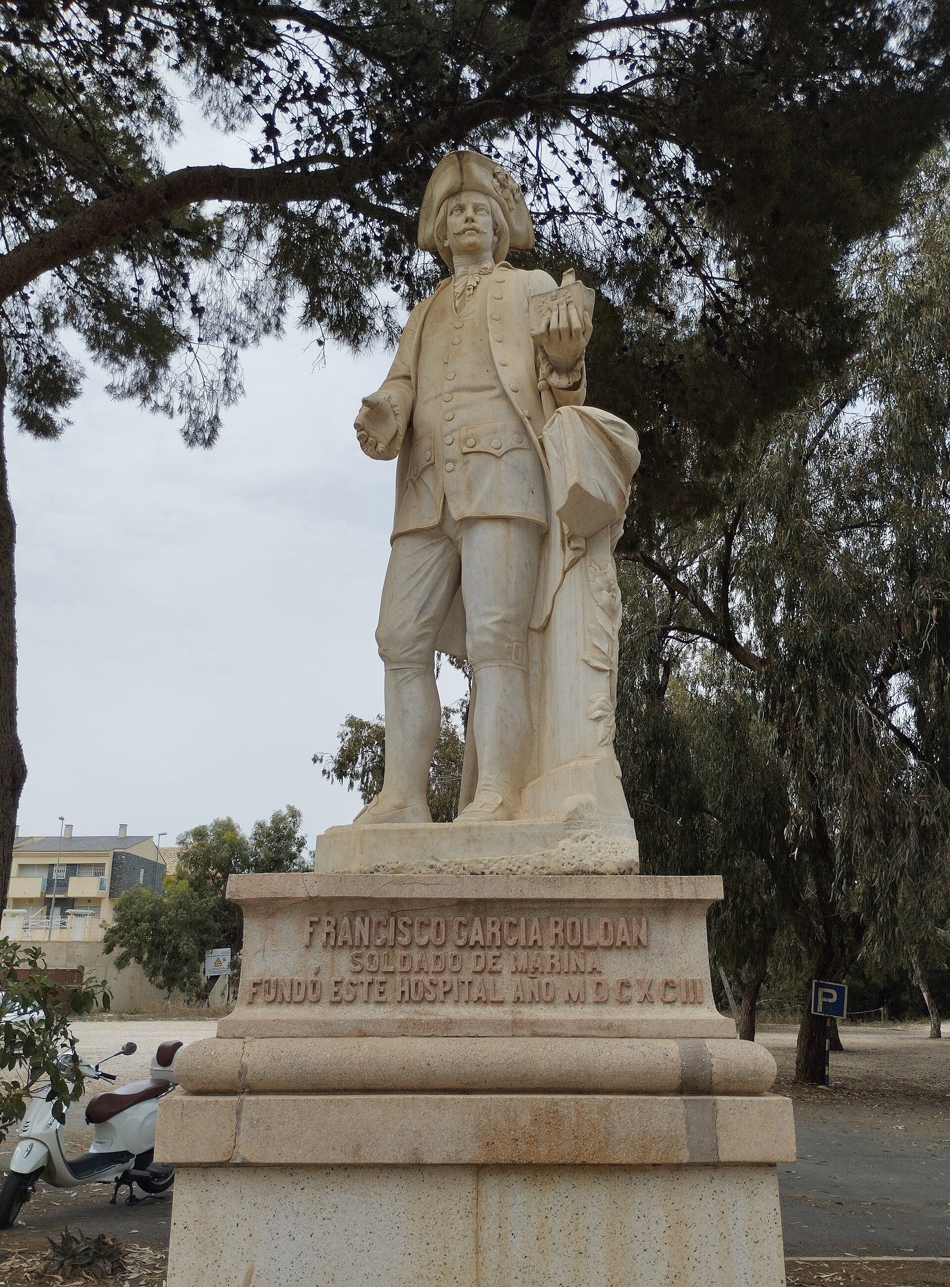 Alt text: Outdoor statue of Francisco García Rojoan, standing with a hat and coat, in a park setting.