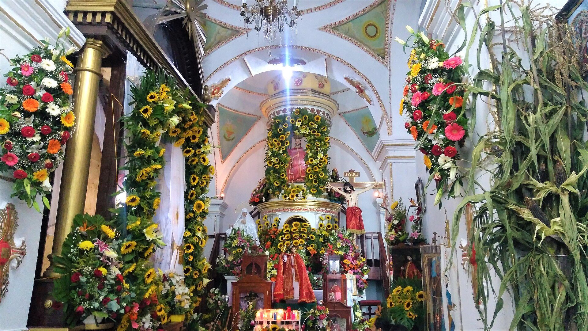 Alt text: Interior of a church with a decorated altar, sunflowers, and religious statues.
