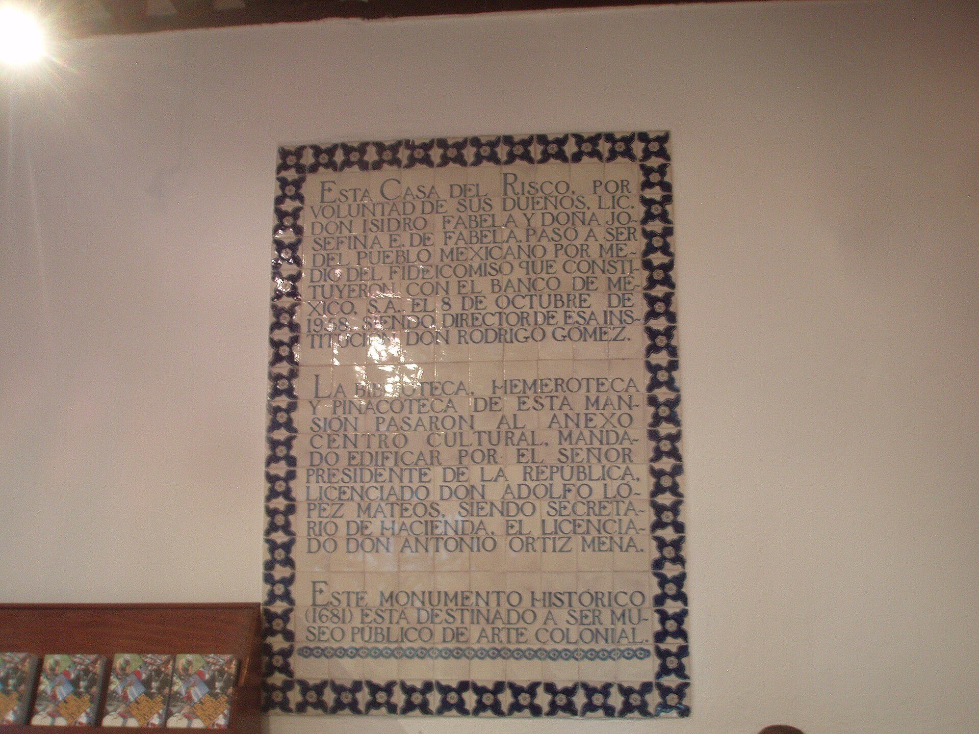 A framed historical text on a wall in a room with wooden furniture.