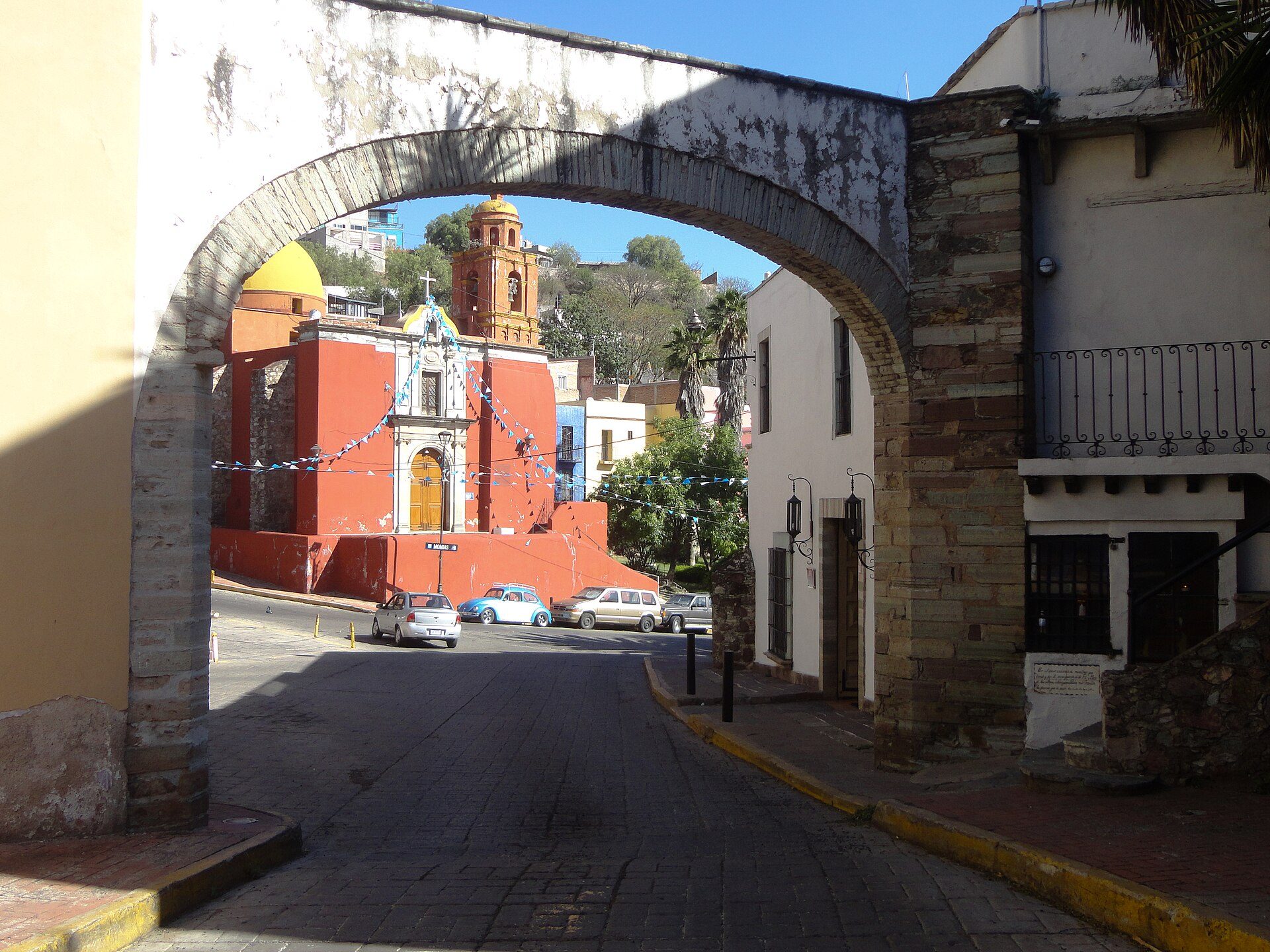 Alt text: Bright room with arched view of colorful church and street.