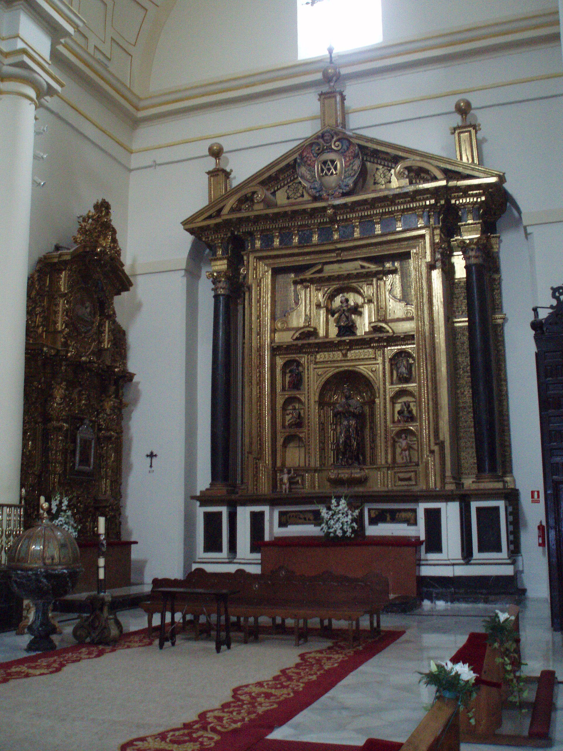 Altar in ornate church with gold decorations, religious statues, and a crucifix.