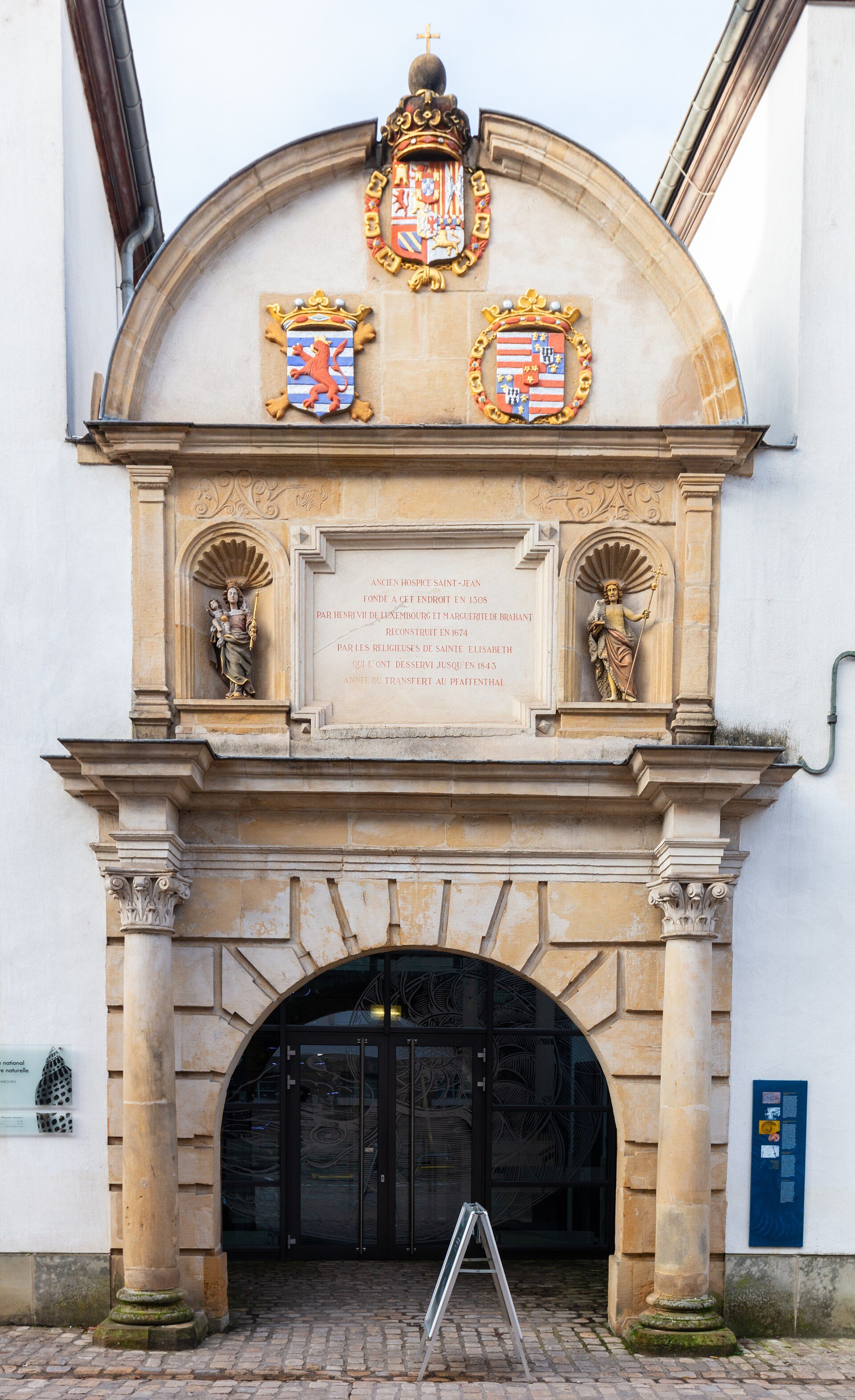 Alt text: Historic building entrance with arched doorway, crests, and stone columns.