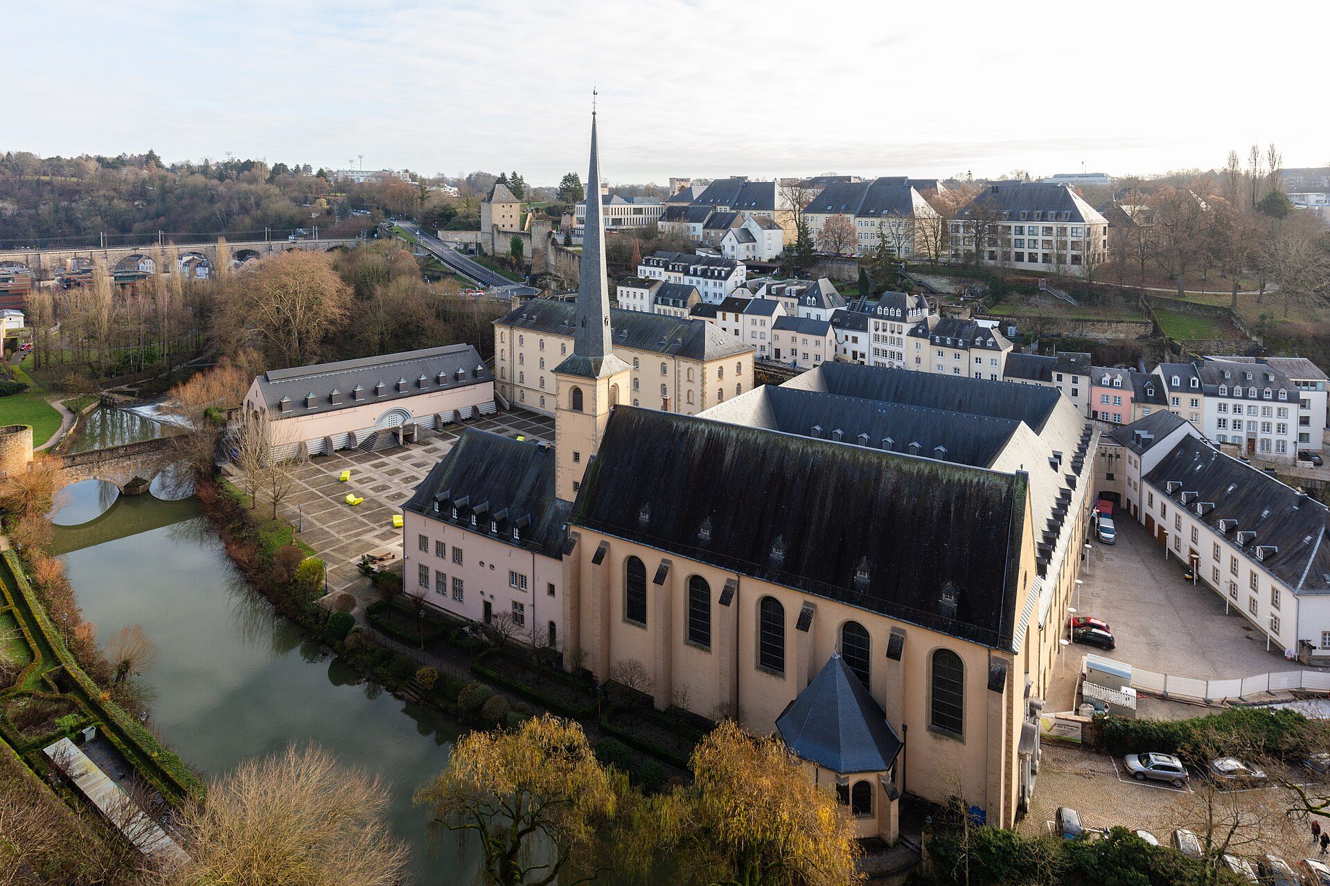 Aerial view of a large church with a tall spire, surrounded by residential buildings and a river.