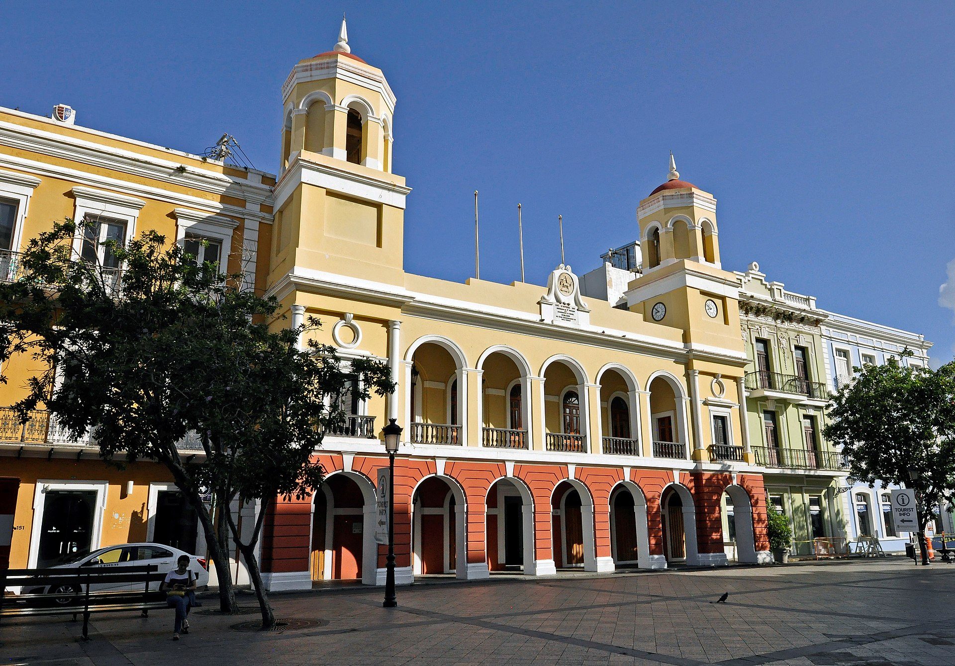 Alt text: Historic building with arched windows, clock tower, and vibrant yellow and red facade.