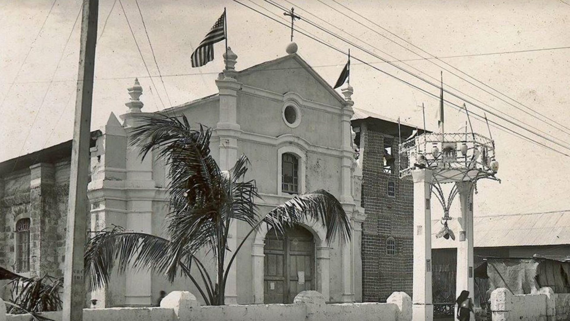 Historic church with palm trees, American flag, and a bell tower.