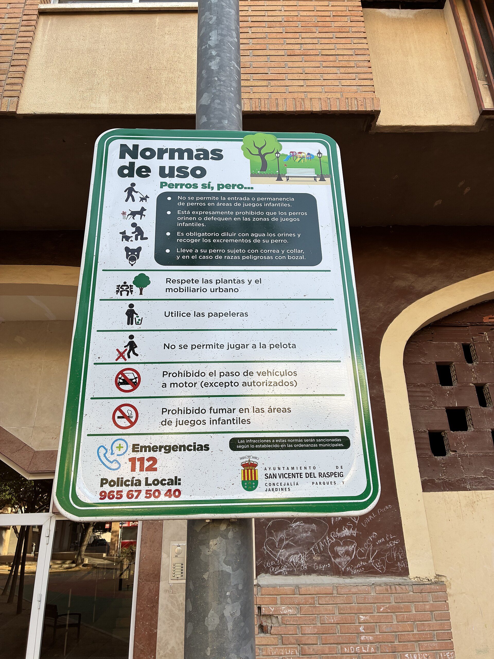 Sign with park rules and emergency contact information.