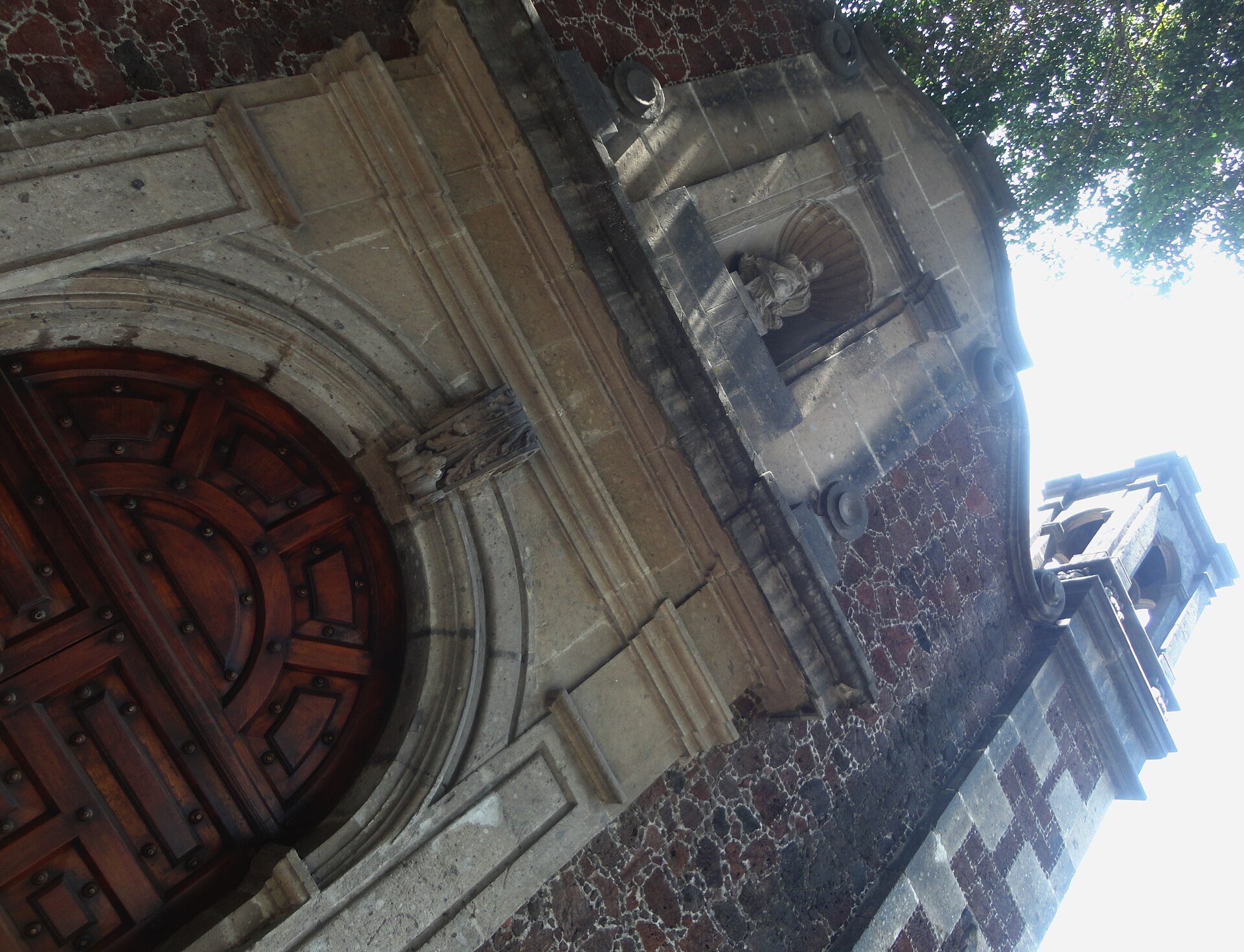 Alt text: Historic church entrance with arched wooden door and stone facade.