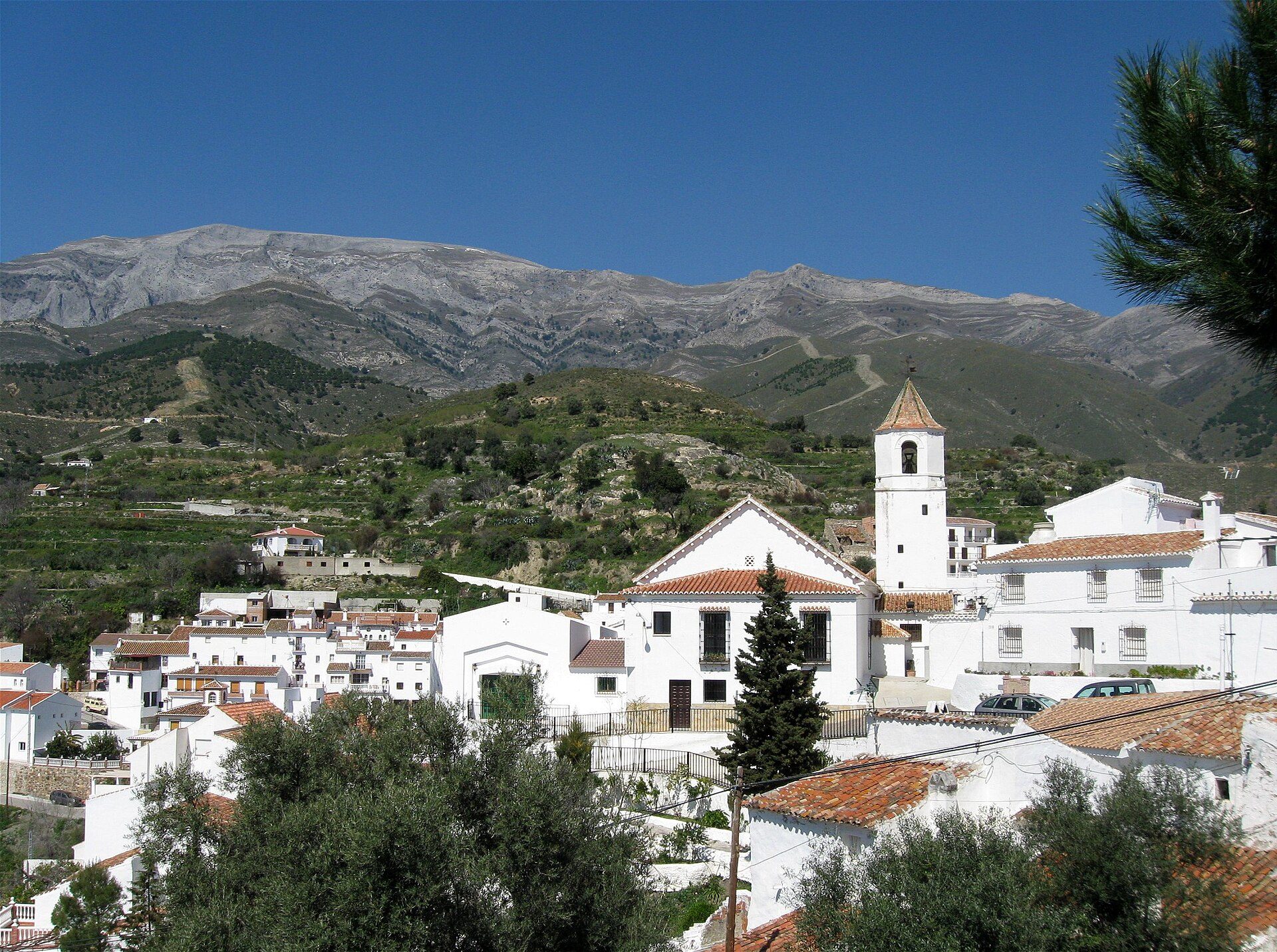 White-walled room with mountain view, featuring a private balcony and modern amenities.