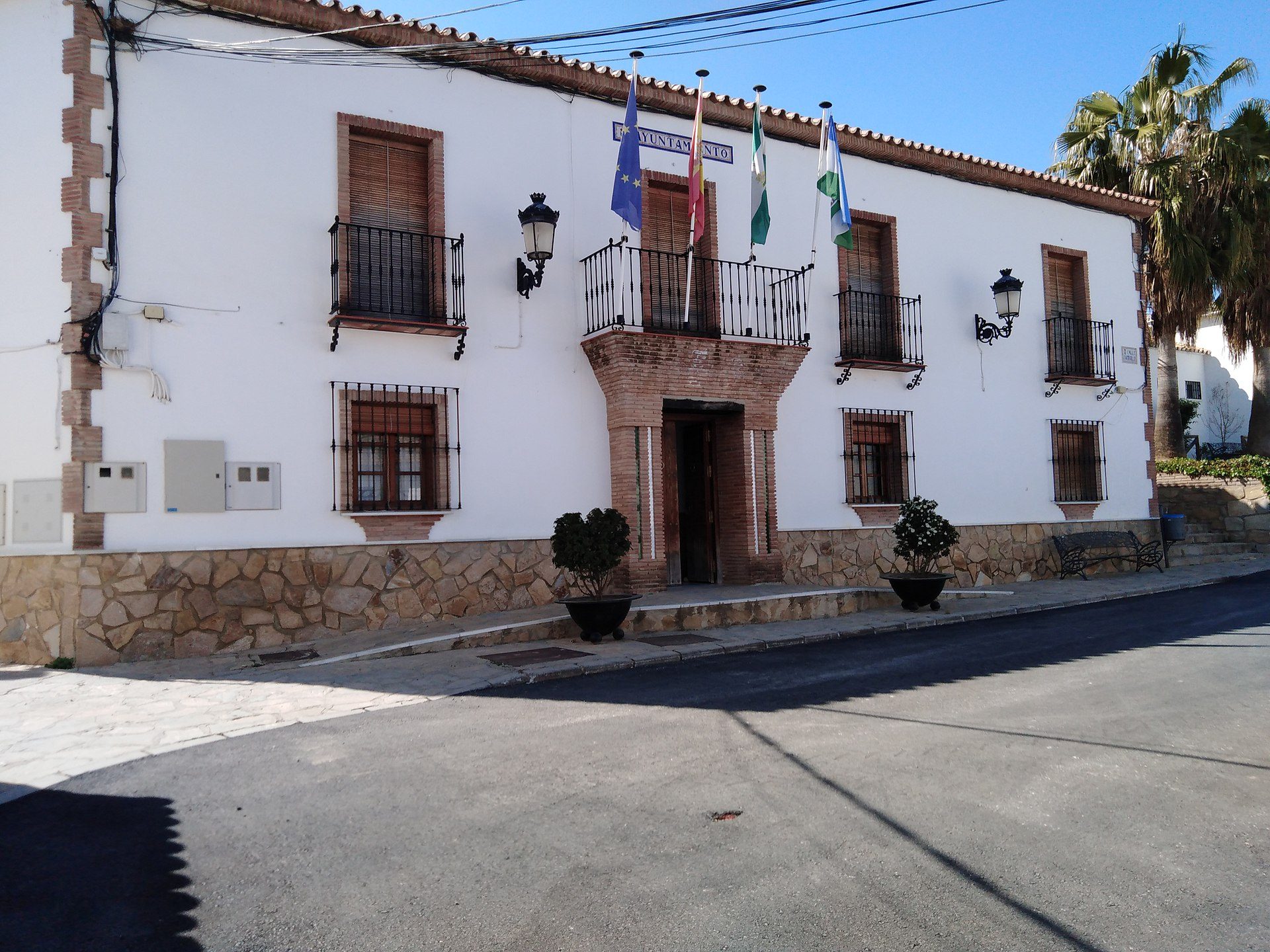 Two-story building with balconies, flags, and stone facade.