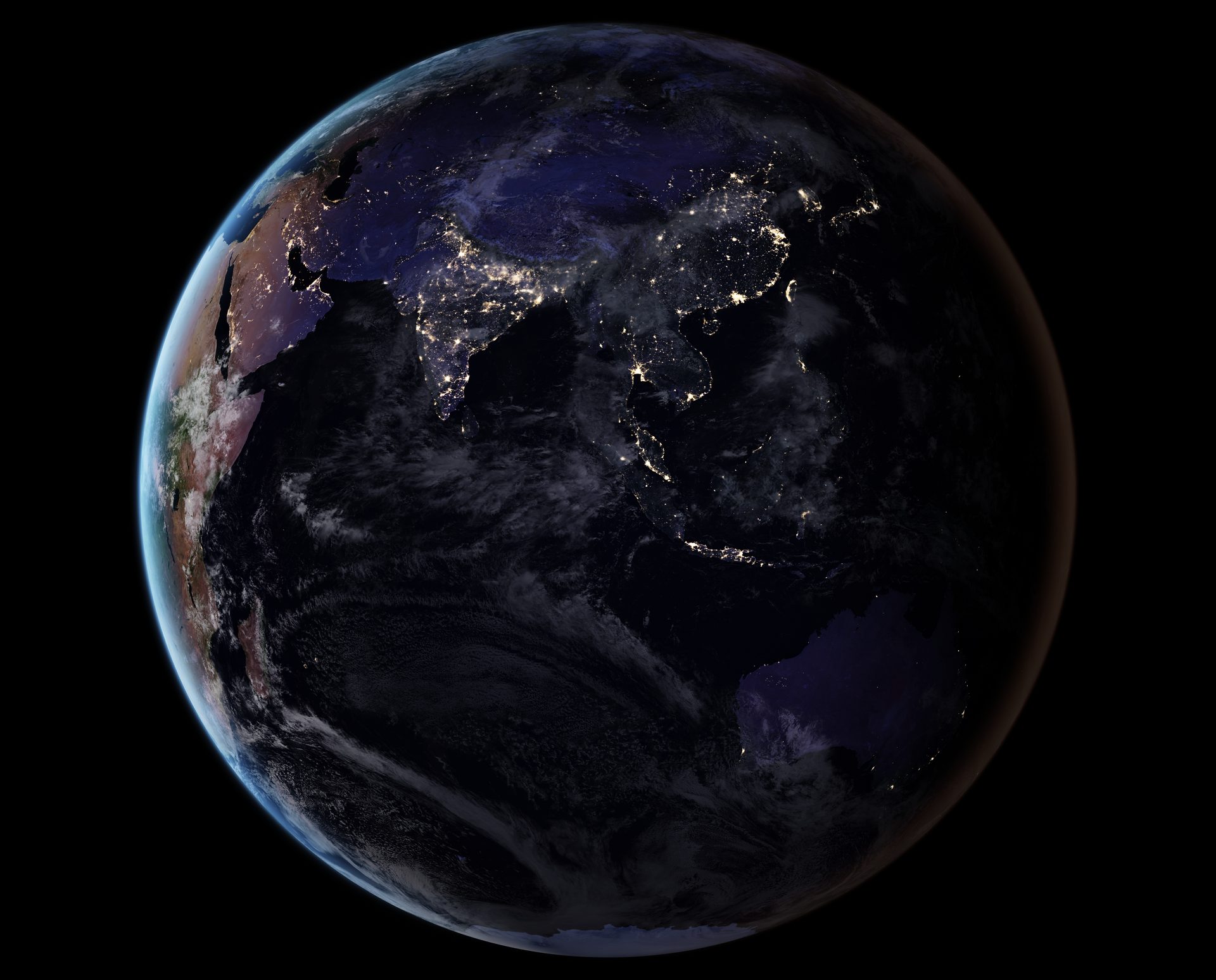 Alt text: Night view of Earth from space, showcasing illuminated continents and cloud formations.
