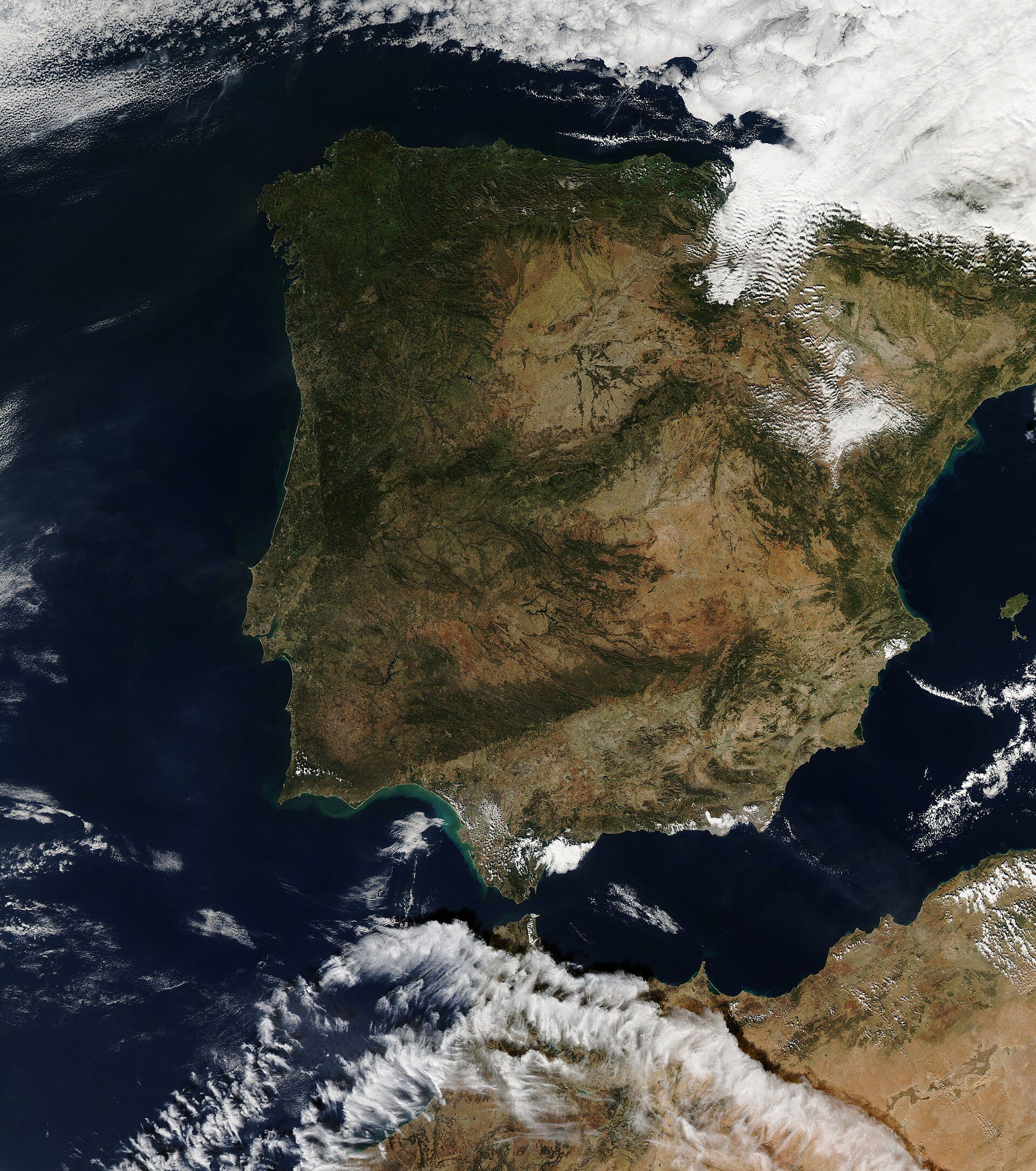 Alt text: Aerial view of a coastal region with mountains and ocean.