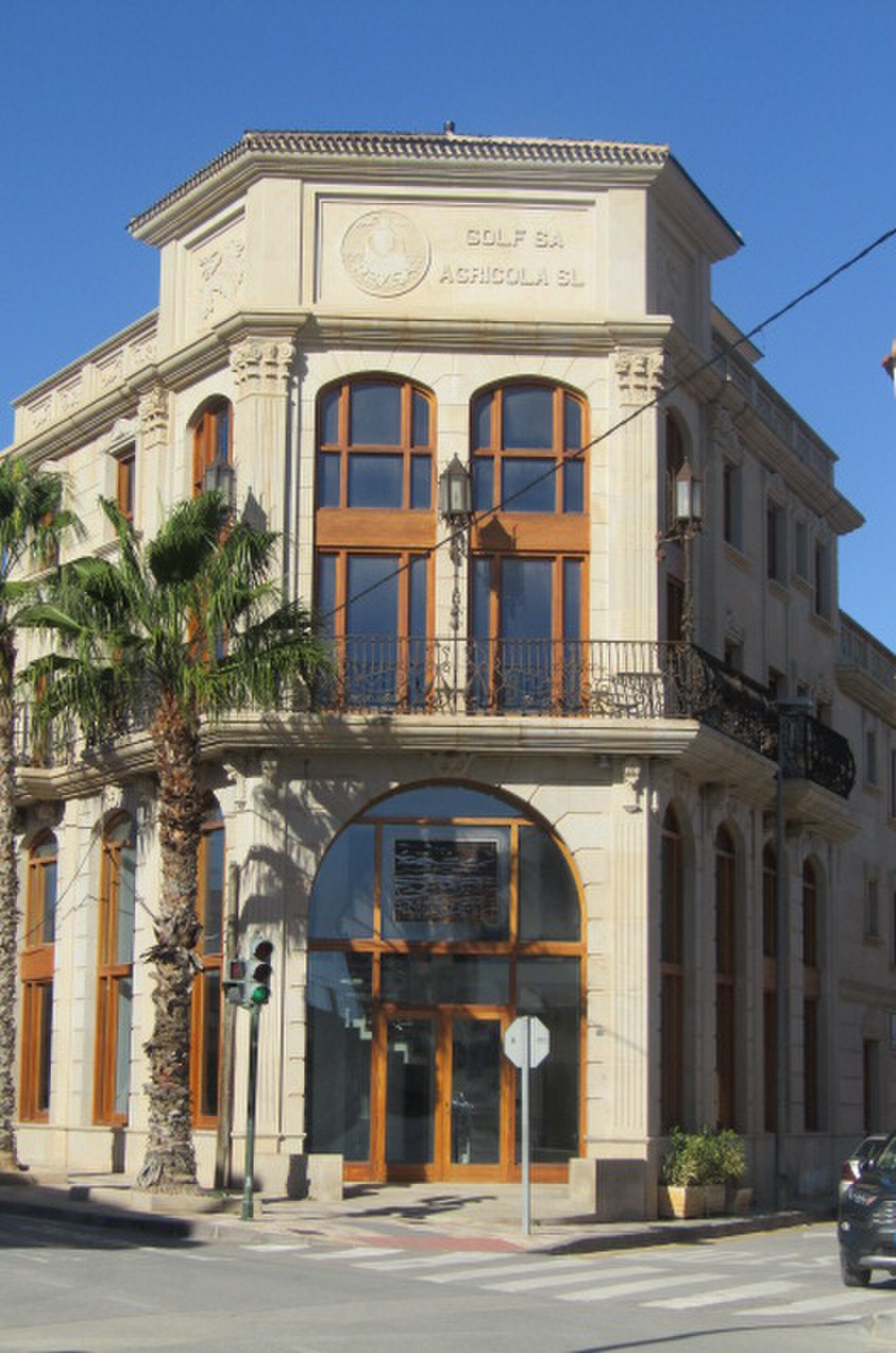 Classic building with large windows, palm trees, and a balcony.